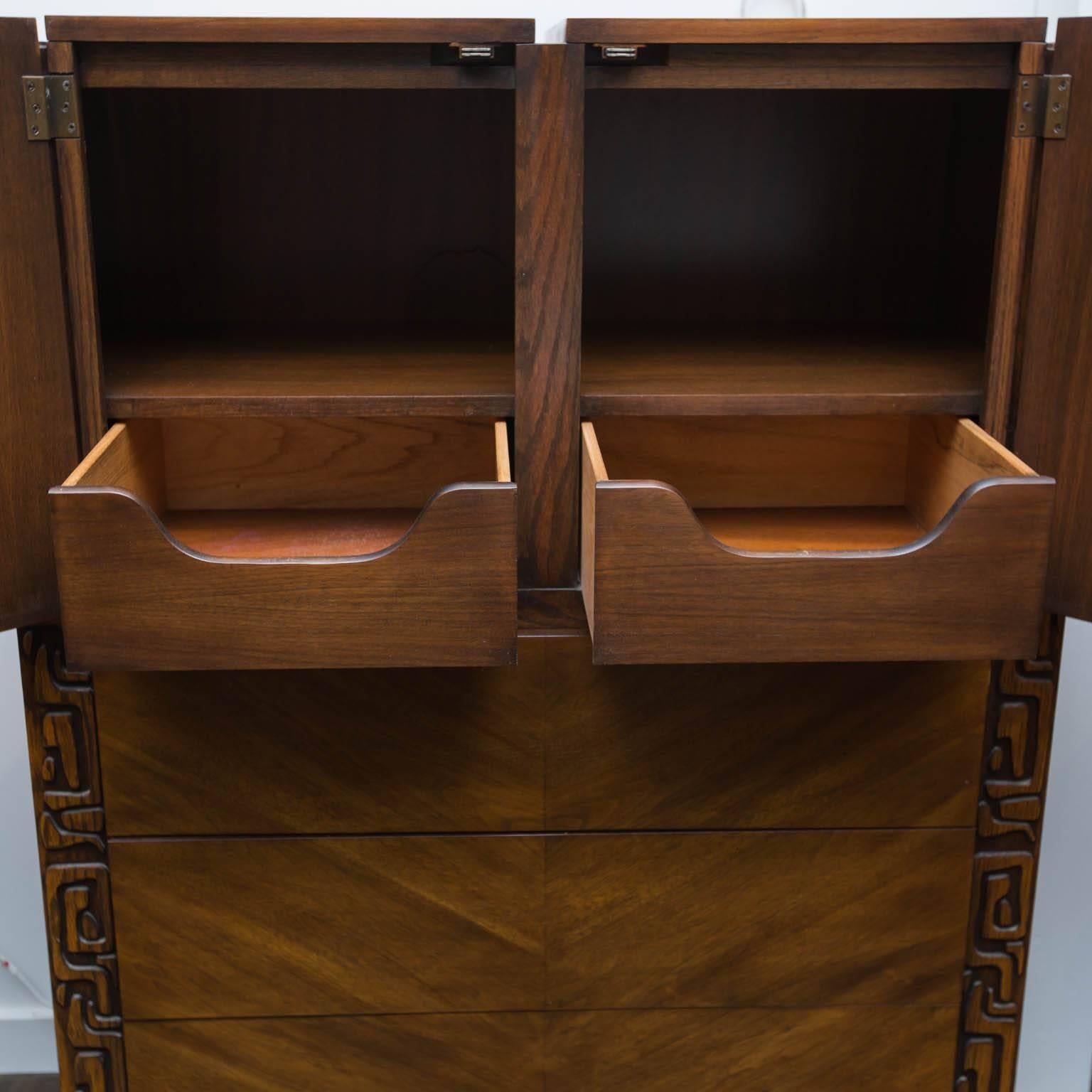 Nice twist on the brutalist movement, with a hint of Kon Tiki. Well built from hardwoods and bookmatched walnut veneers, this piece features an upper compartment for sweaters an bigger items with two small drawers and three generous drawers below