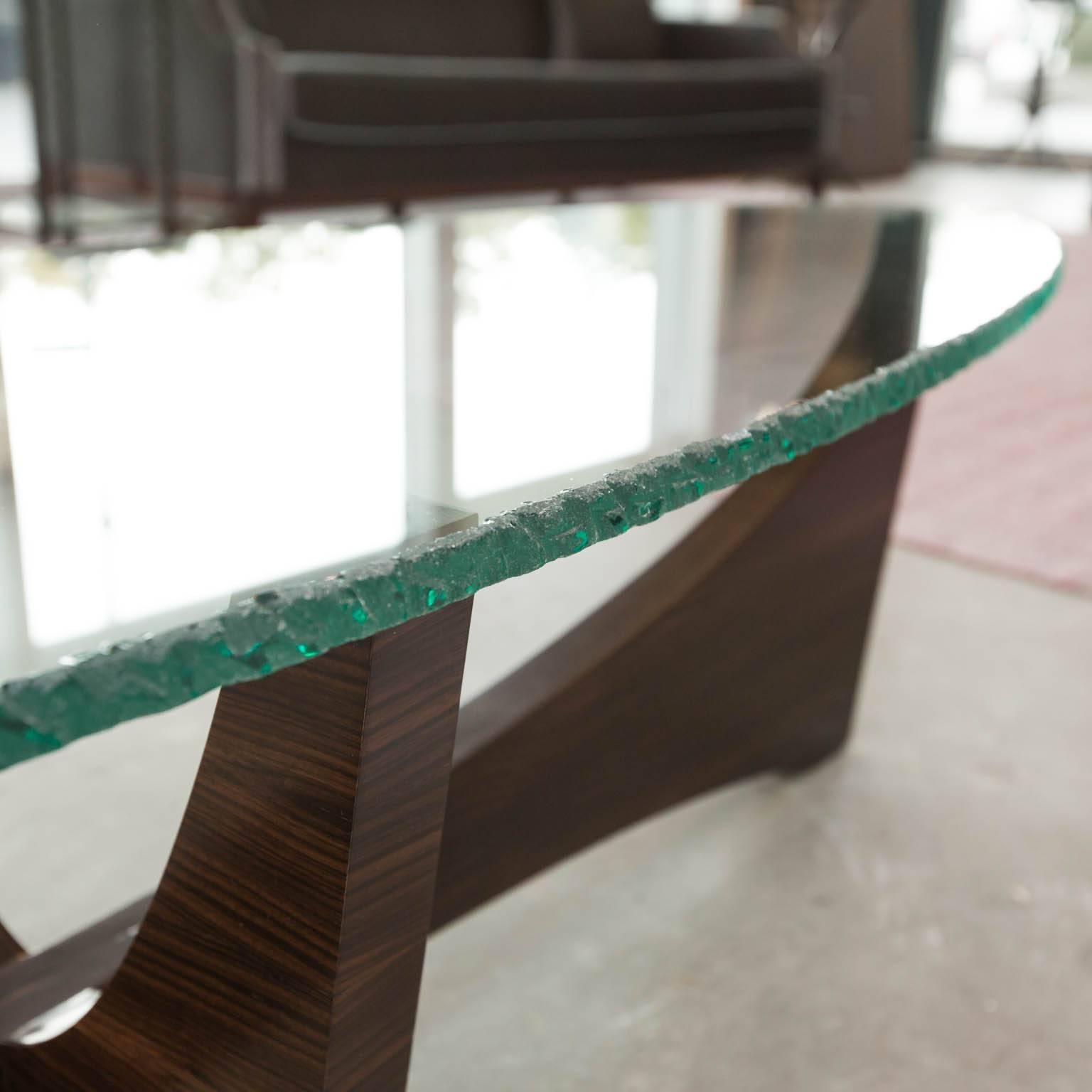Classic surfboard shaped 3/4 inch hand chiseled edge glass sits upon a solid hardwood base with Macassar veneers and a French polish finish.