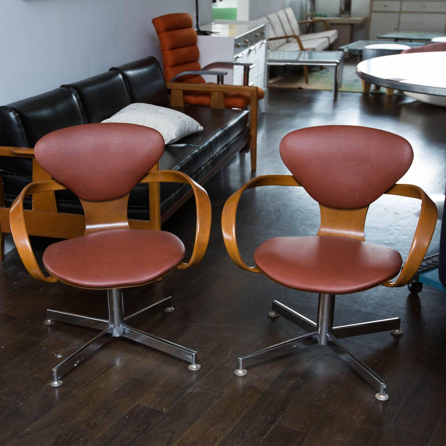 Most likely originally made by Plycraft, these newly refinished chairs were at sometime over the years switched from wooden legs to metal bases. Original leather is in good condition.