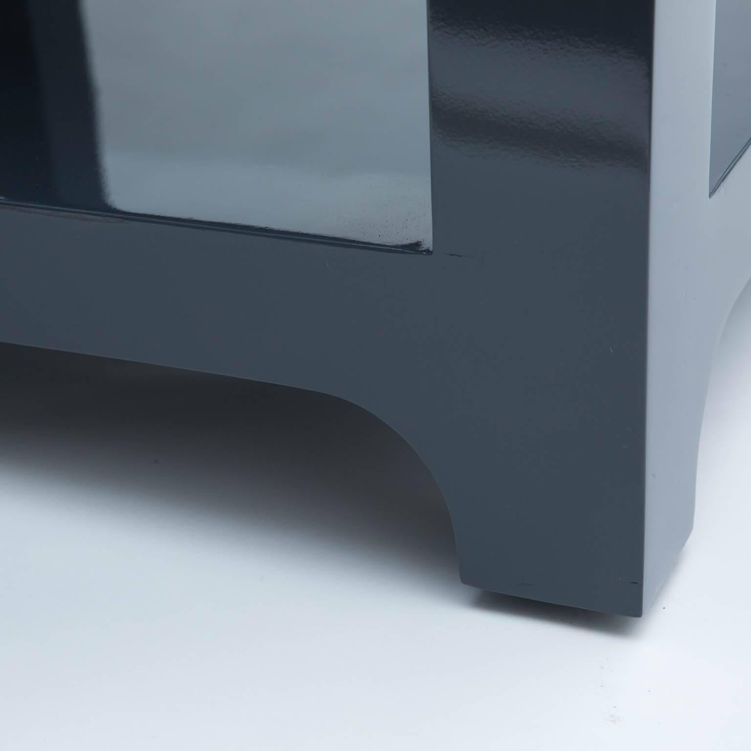 Large, dark grey, lacquered end tables polished to a piano finish. 