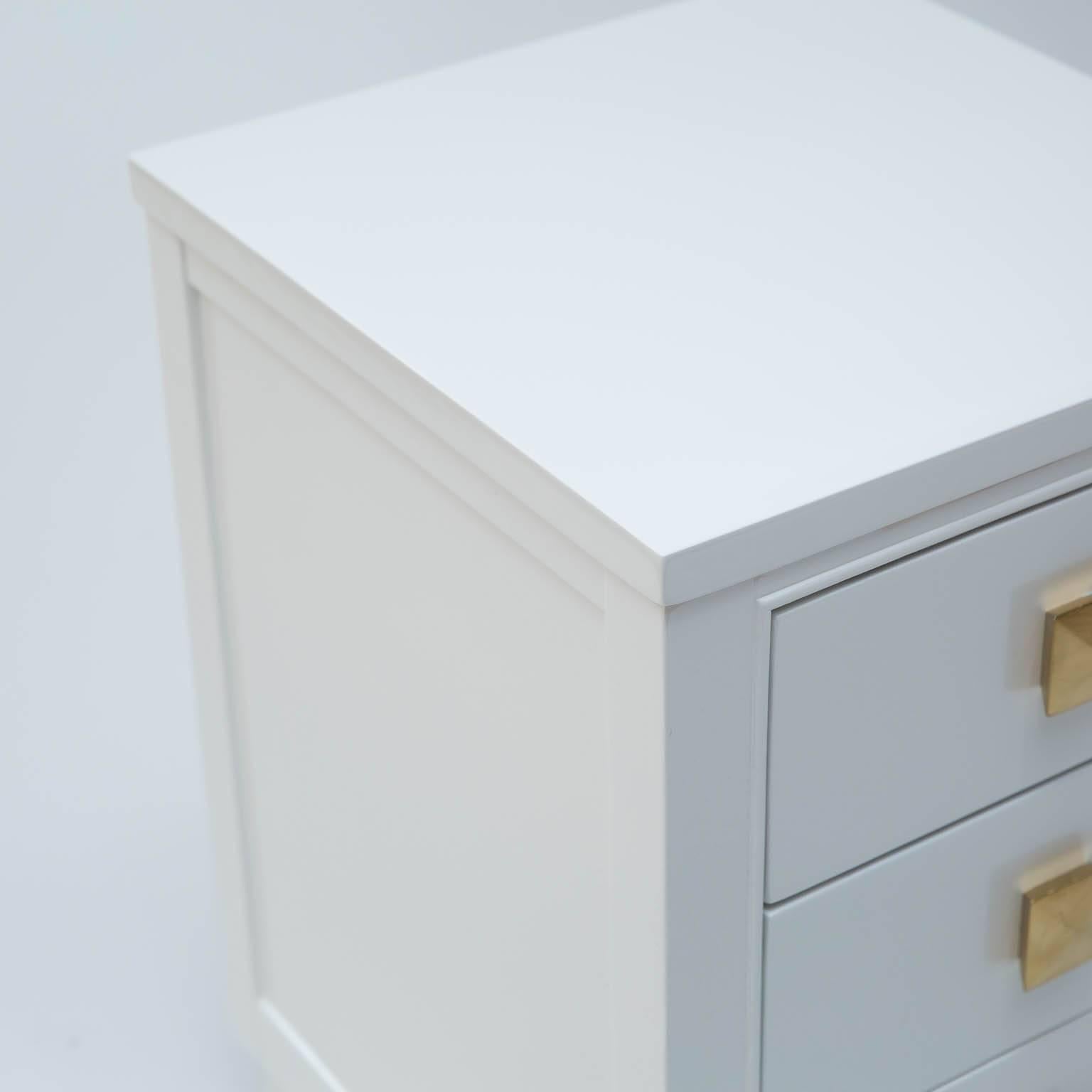 Vintage set of 1950s era three-drawer nightstands given a new lease on life, freshly lacquered in white dove. Solid wood drawer pulls are lacquered in a metallic gold.