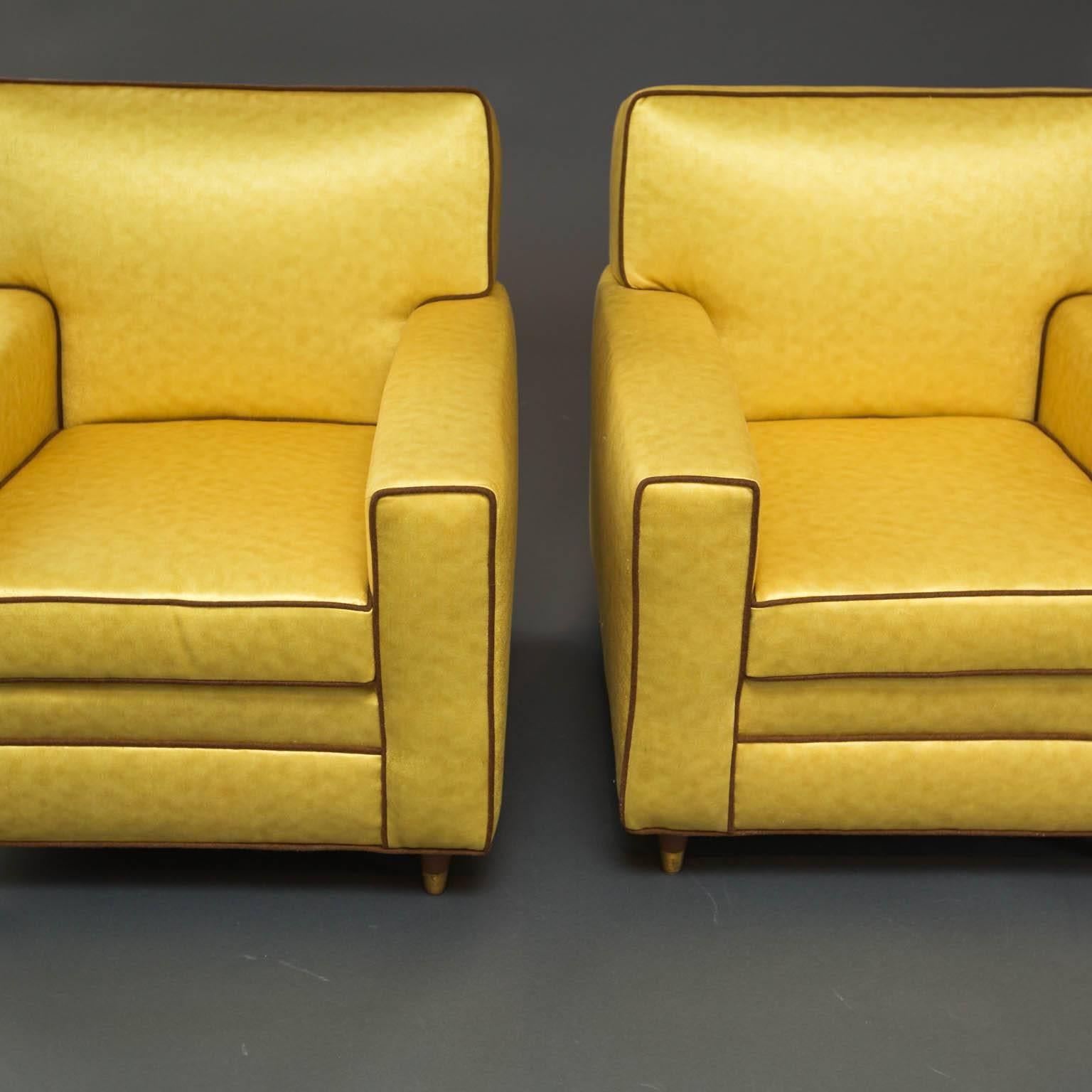 Newly reupholstered mid-century modern era tuxedo club chairs in dramatic yellow Schumacher fabric with brown accent piping.