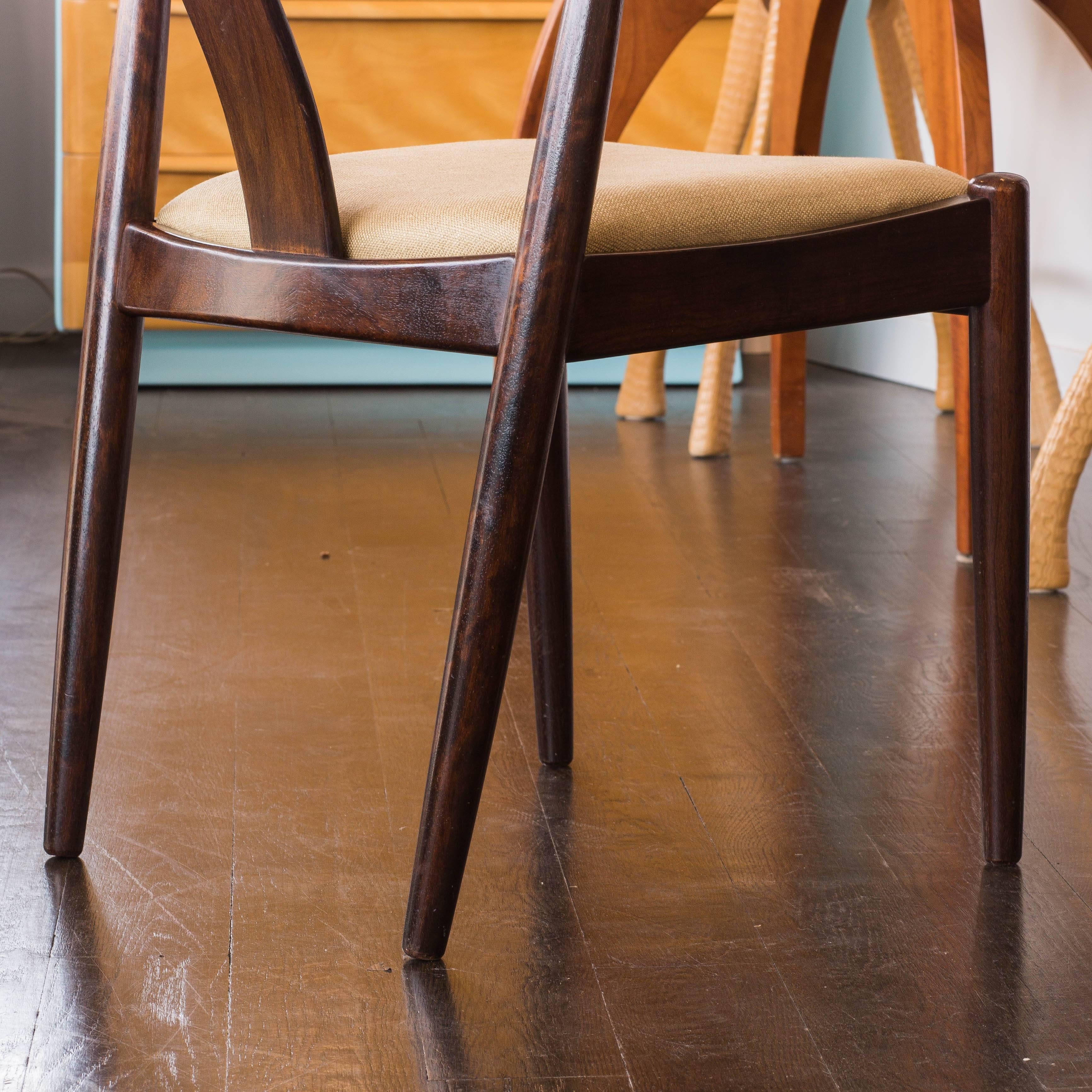 A set of 4 rosewood Dyrlund curved-back side chairs. The chairs have newly reupholstered beige linen seats. Dyrlund furniture is known for their quality craftsmanship. 