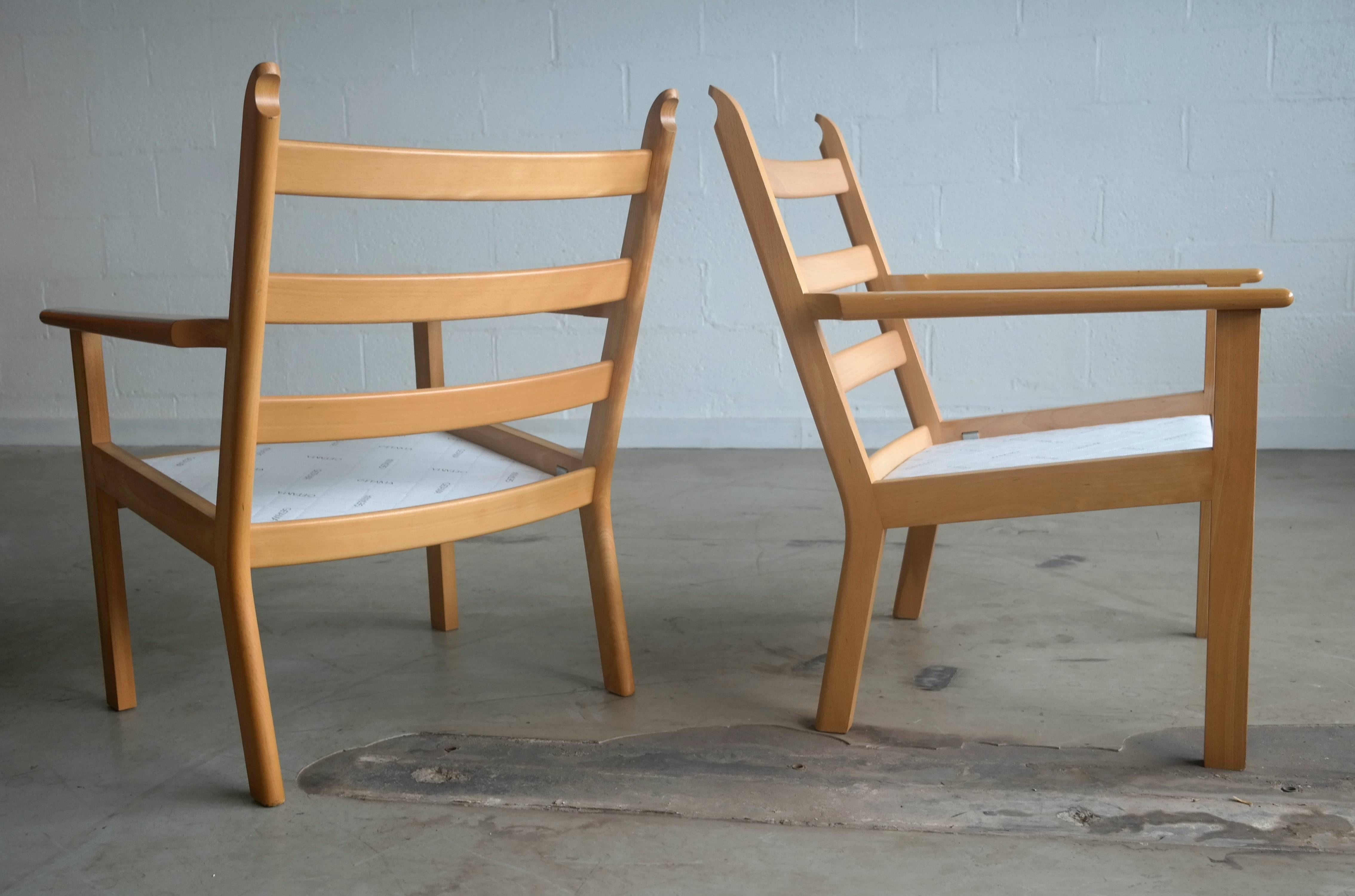 A nice pair of great Danish easy chairs model GE 284 designed by Hans Wegner for GETAMA, Denmark. Chairs are made of solid beechwood and retains original wool fabric by Kvadrat. Some slight scuffing and scratches based on normal wear but overall in