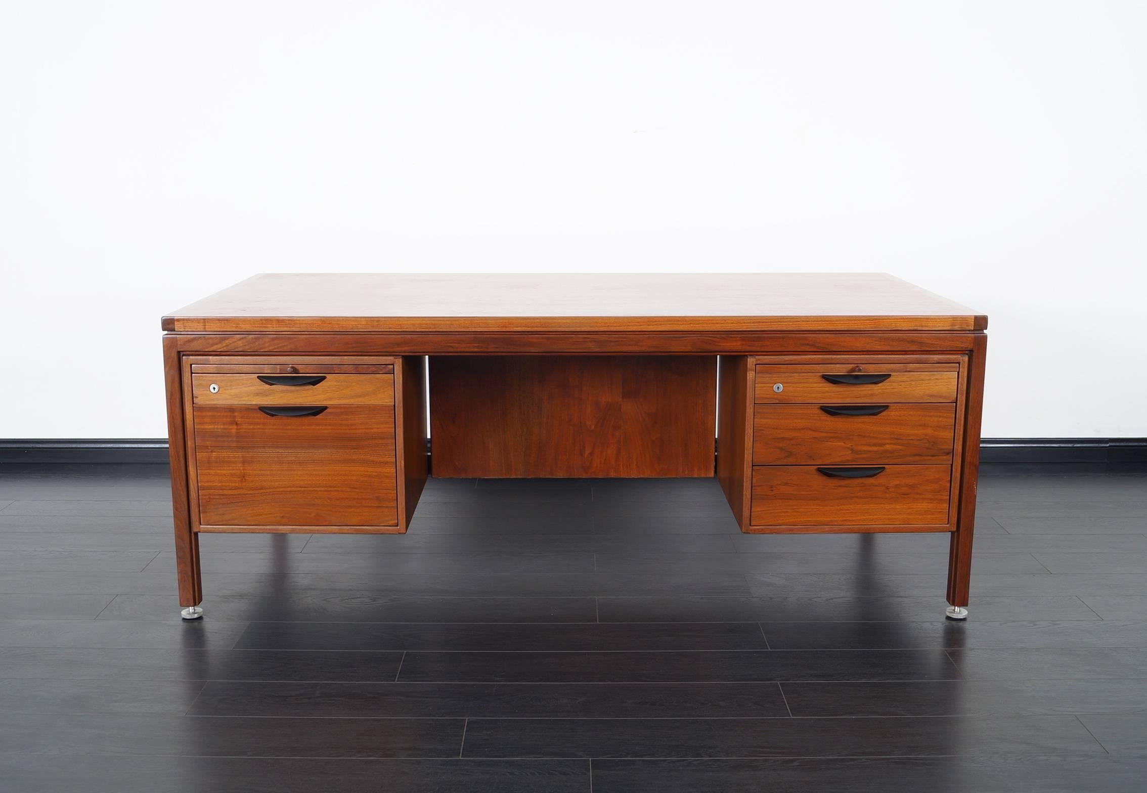Fabulous midcentury executive desk designed by Jens Risom for Risom Design. Features gorgeous walnut grain and original black sculpted handles. It offers four pull out drawers and one file drawer.