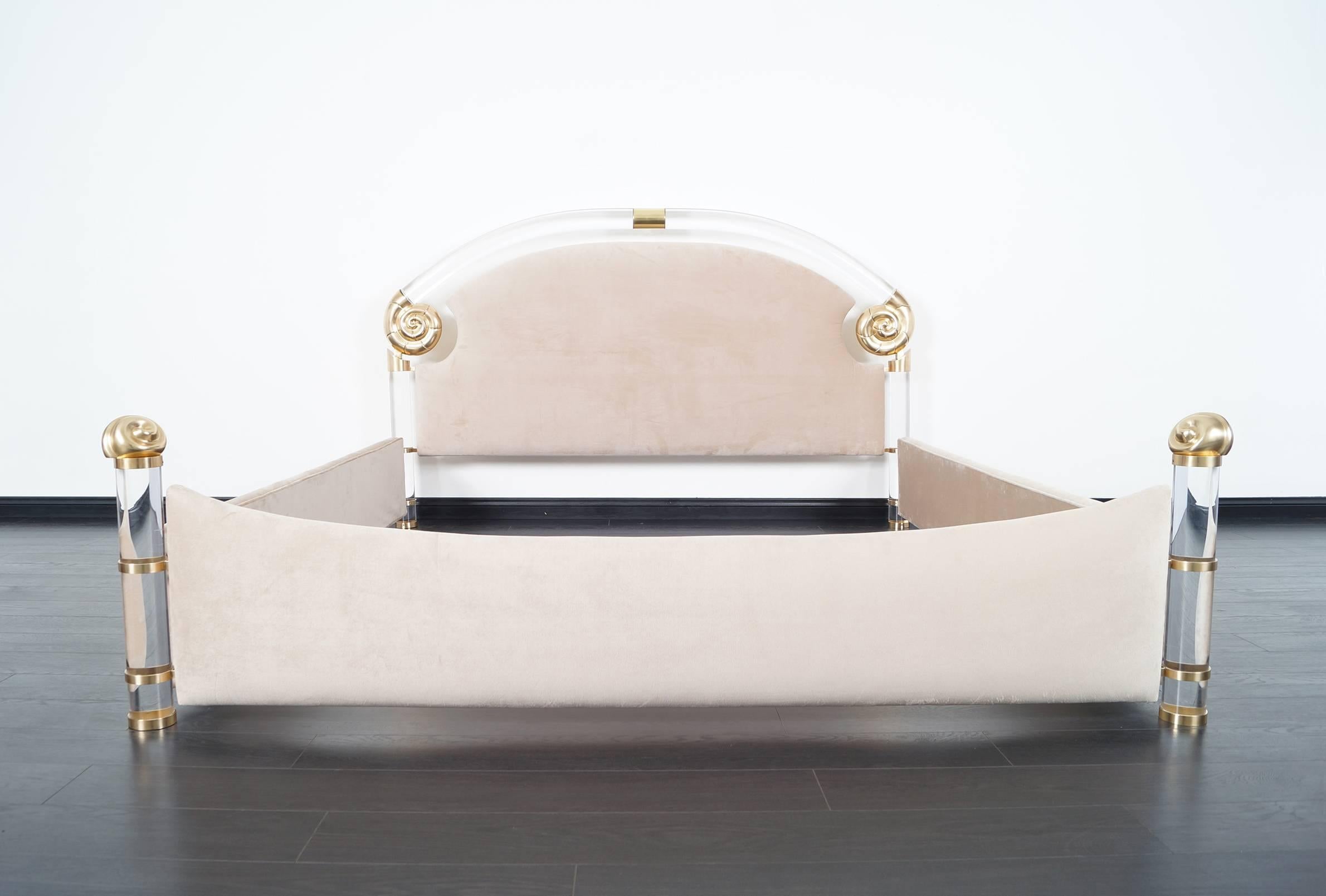 This glamorous vintage Lucite and brass king-sized bed was designed by Marcello Mioni. The bed is constructed with solid Lucite poles and large brass nautilus that gives the bed a unique design.