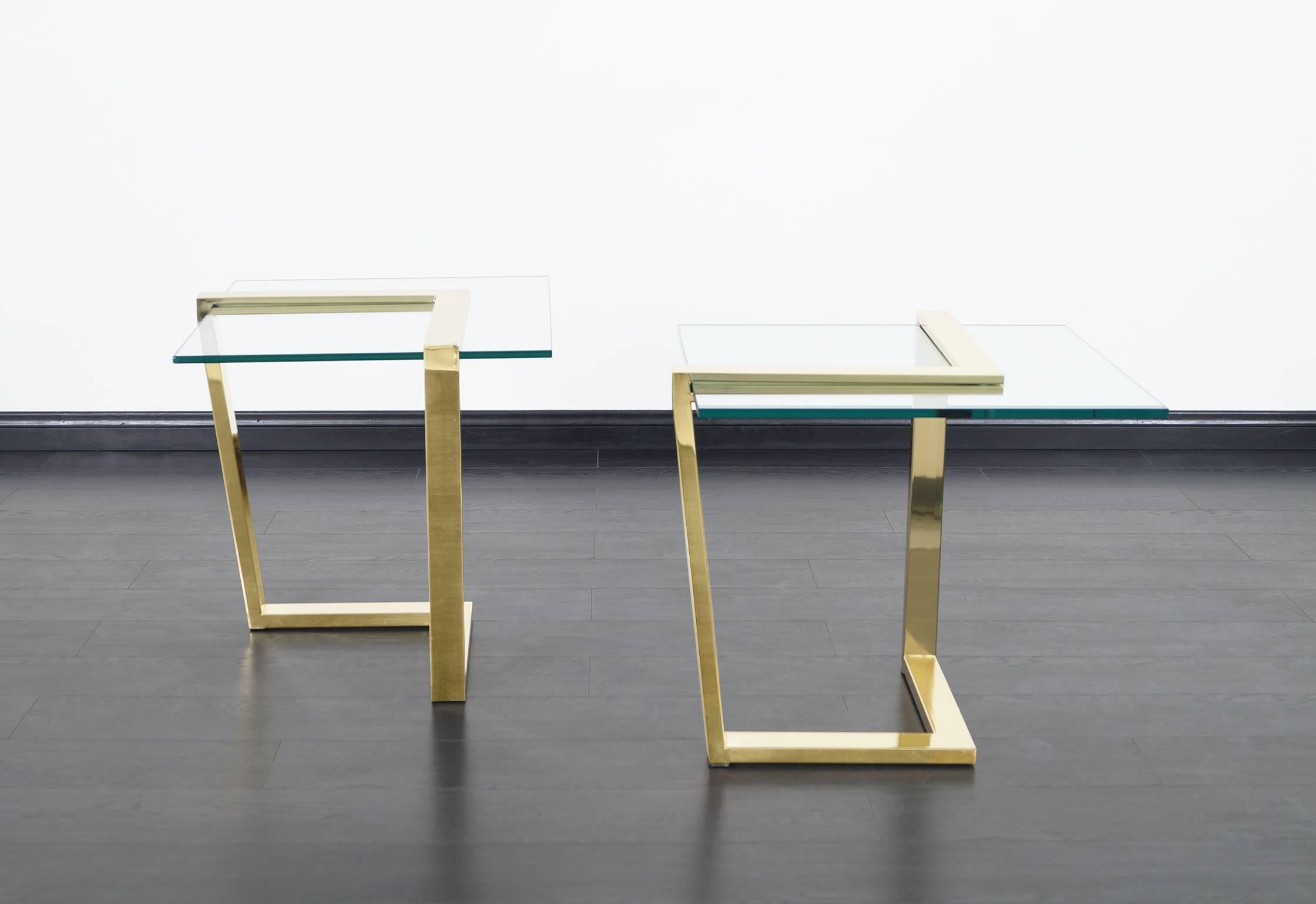 Elegant vintage brass cantilevered side tables manufactured by DIA (Design Institute of America), circa 1980s. These tables have a modernist design in which the architecturally constructed chevron-shaped polished brass bases stand out. The bases