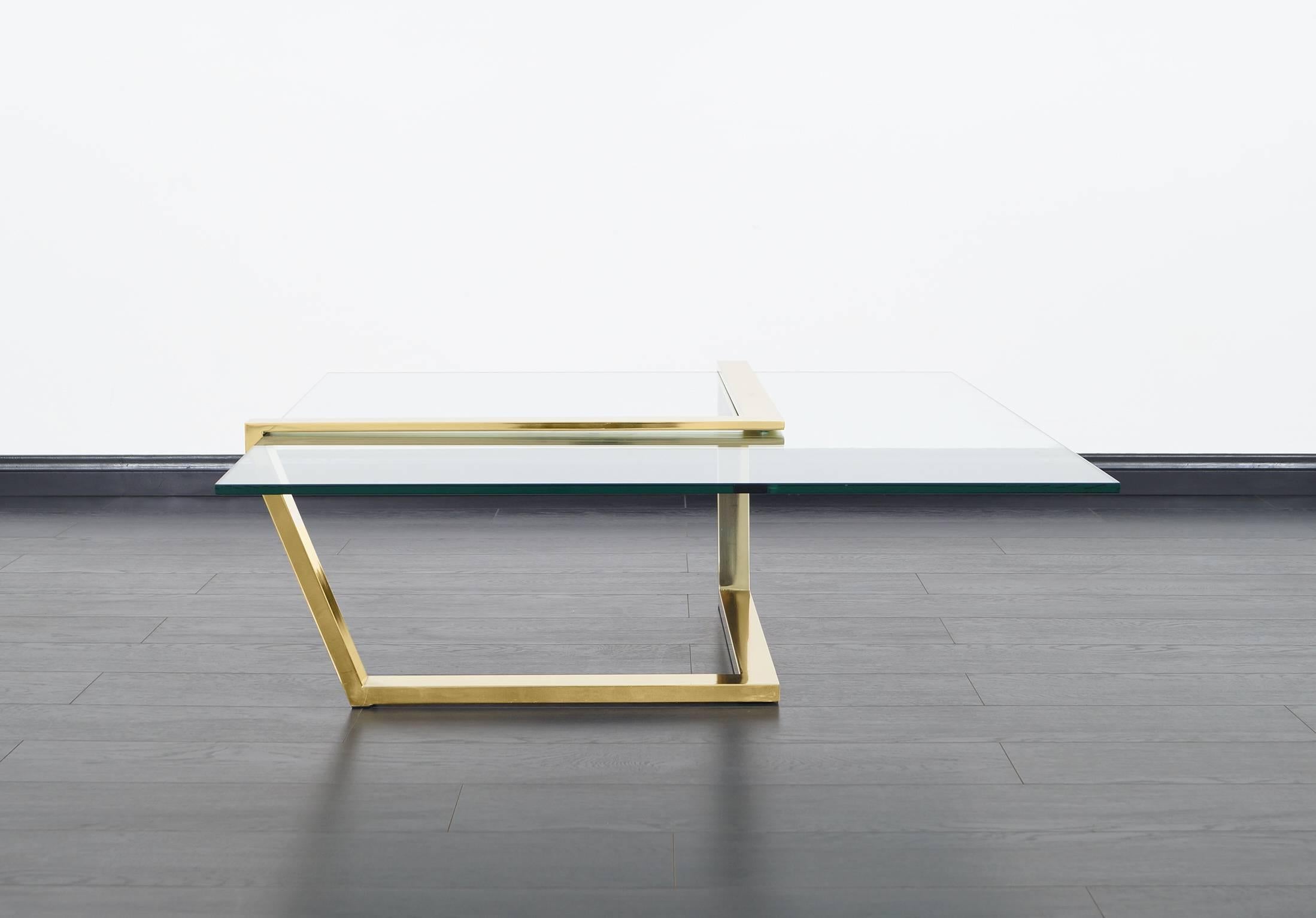 Modernist brass and glass cantilevered coffee table by Design Institute of American. The thick square glass slides into the chevron shaped brass base, giving the appearance of a floating glass top.
