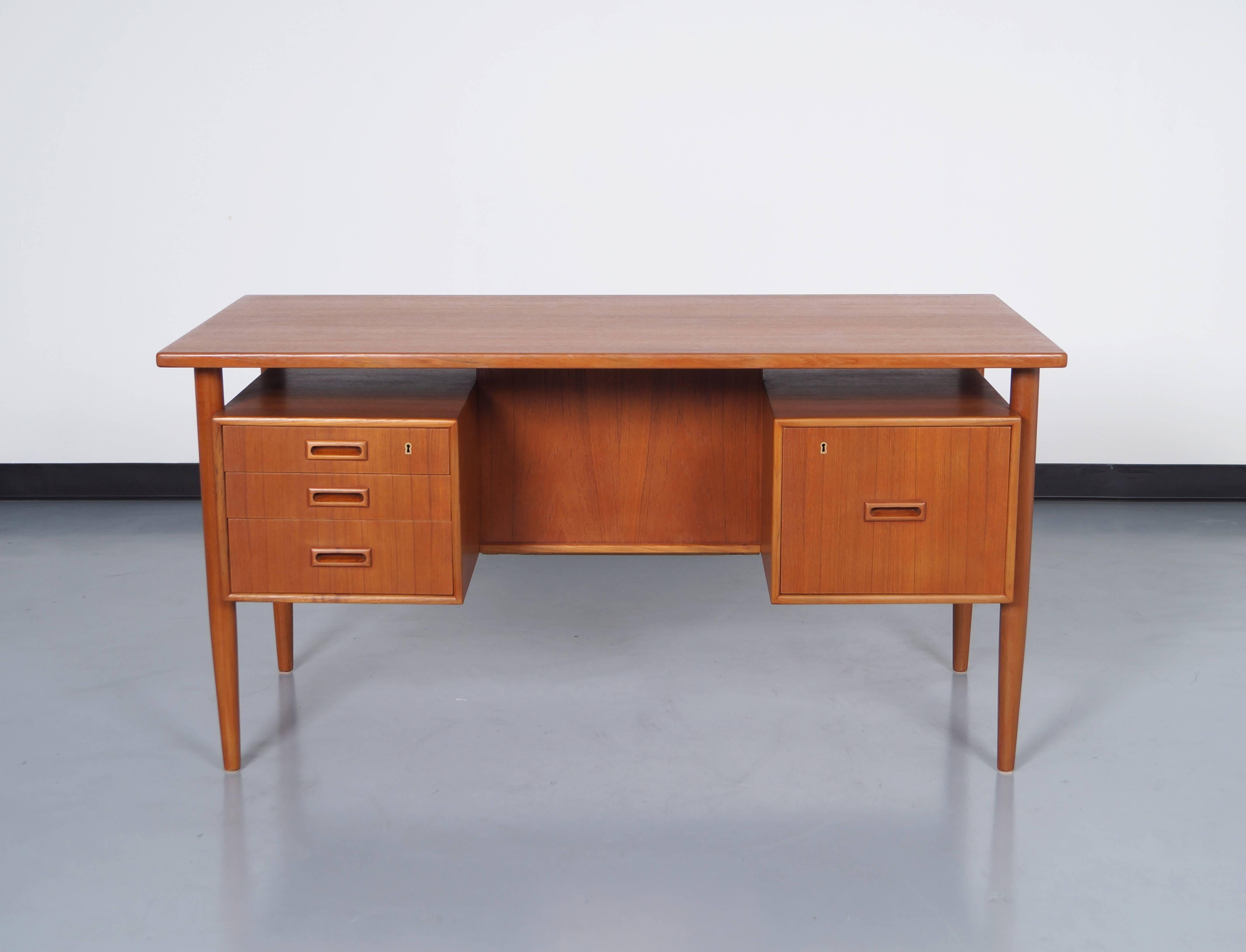 Danish modern floating top desk features three drawers on the left side and one file cabinet to the right. A rear storage space for display.