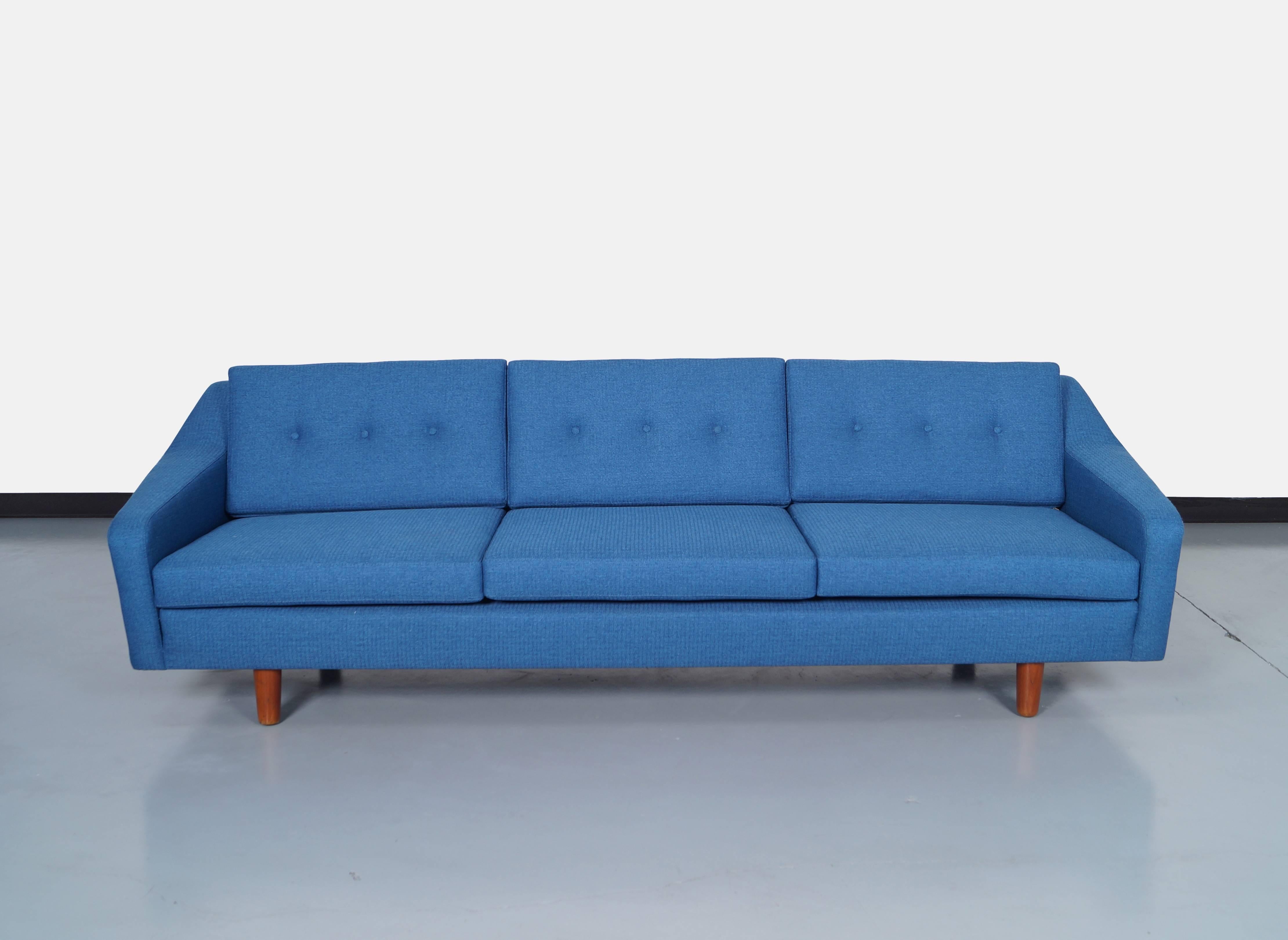 Danish modern sofa designed by Illums Bolighus. Features a sculptural armrest with an elegant design.