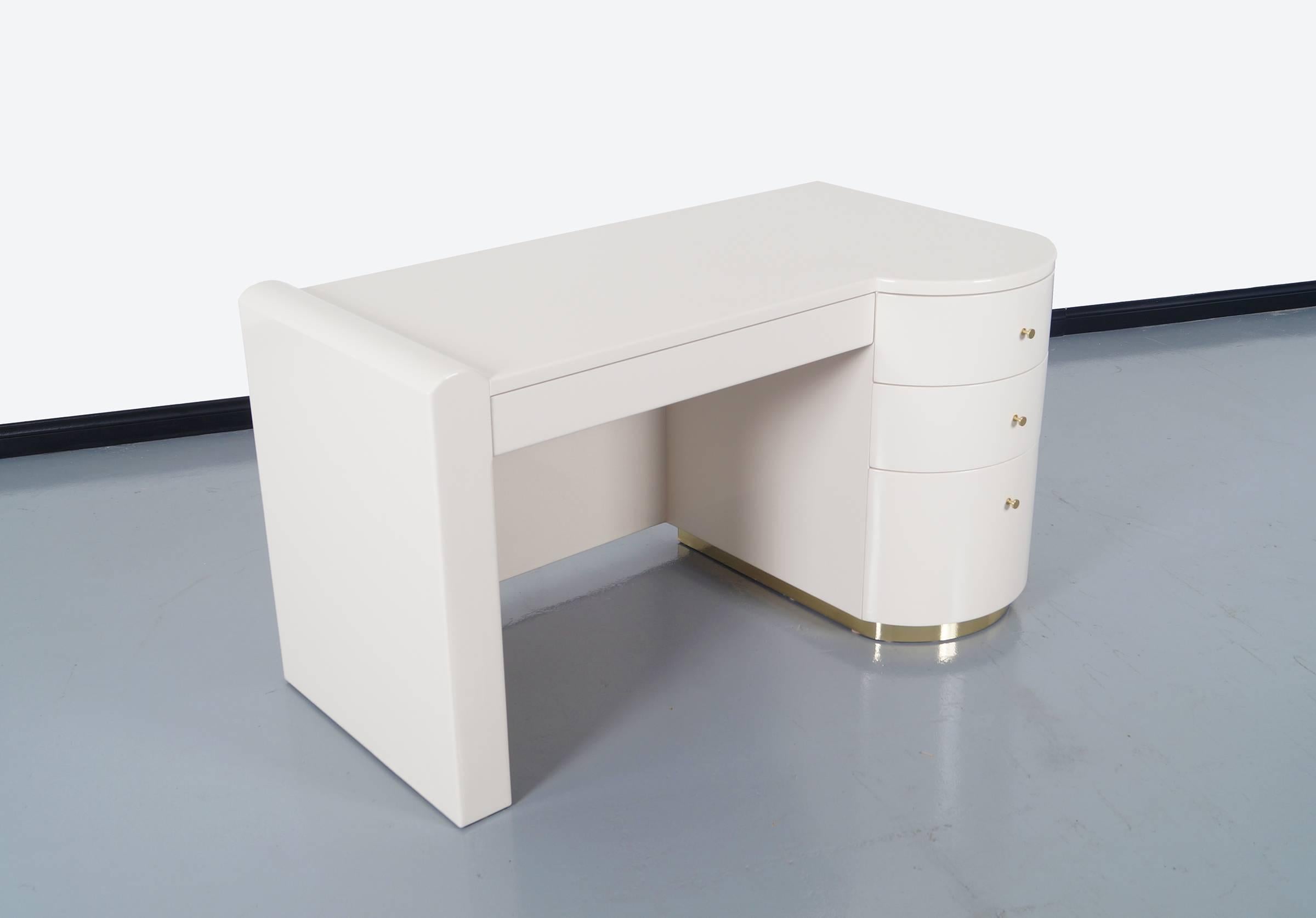 Vintage white polished lacquered desk. Features four pull our drawers with solid brass handles and covered with a brass around the base.