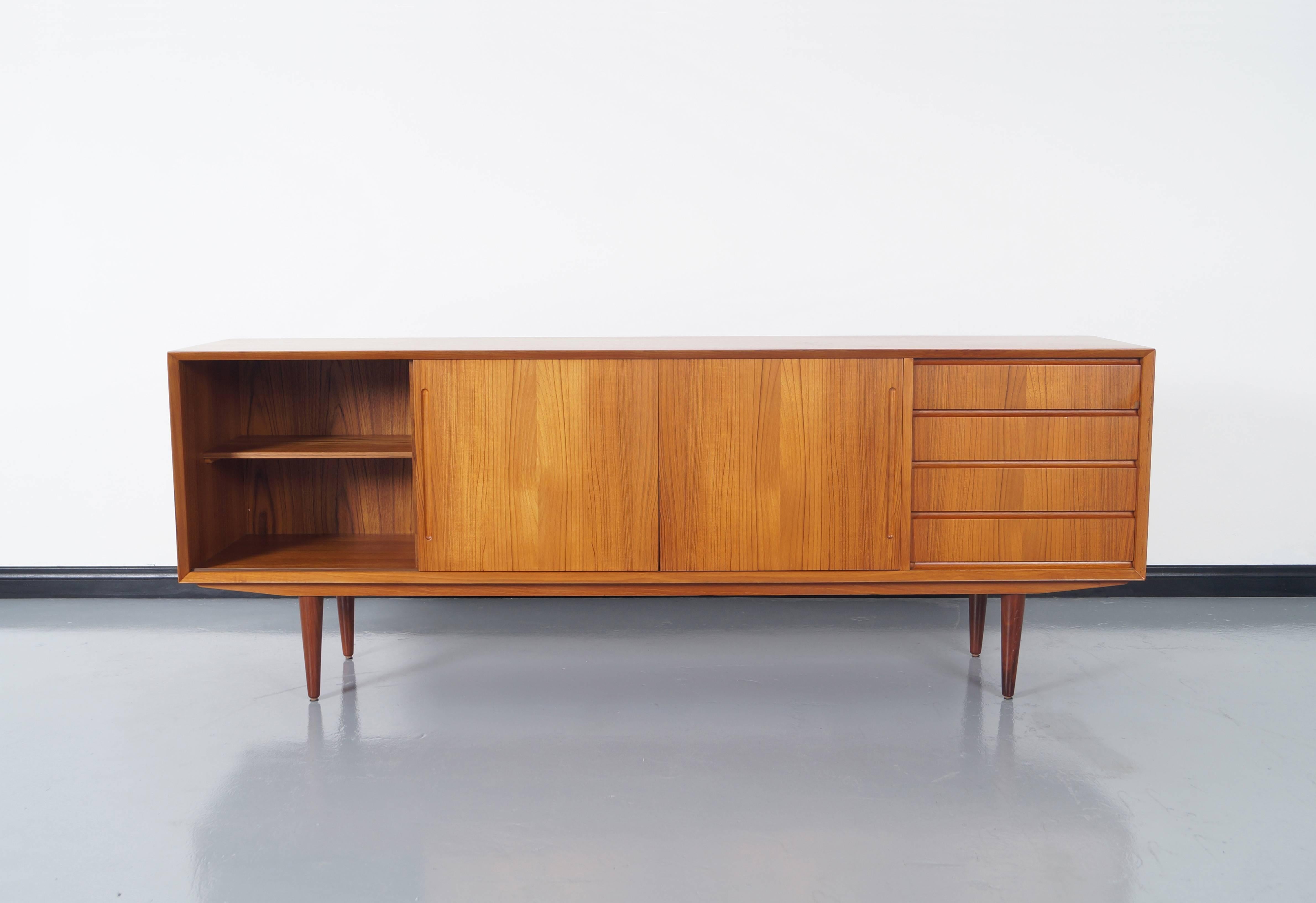 Amazing Danish modern teak sideboard by Alderslyst Møbelfabrik. This piece features with sliding doors and one adjustable shelf on the left side. The right side has four pull-out drawers for added storage.