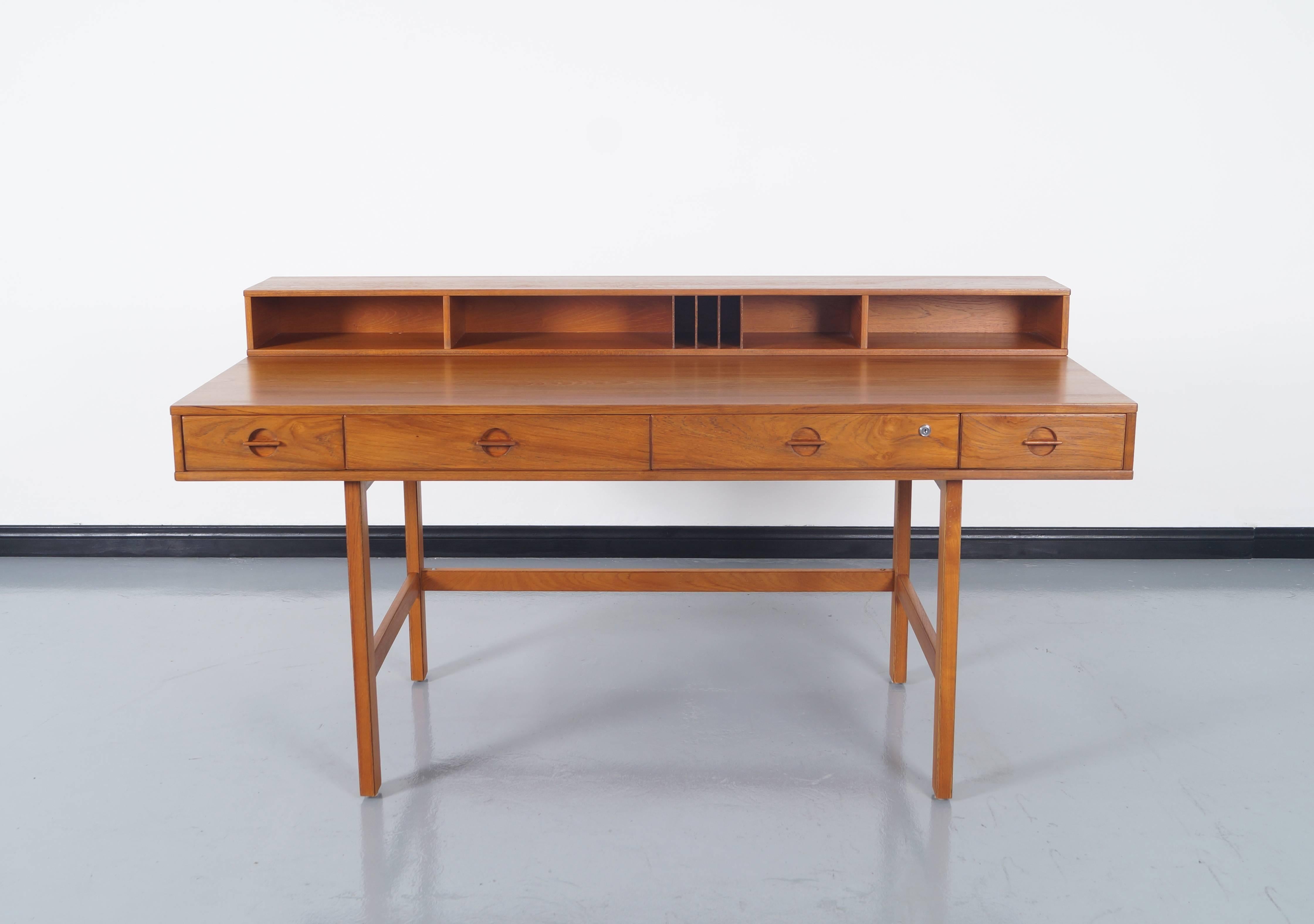 Danish teak desk has a flip-top to extend the desk top for more working space. Contains four dovetail drawers and storage slot in front and additional storage space in the back. Measures: Expands up to 38