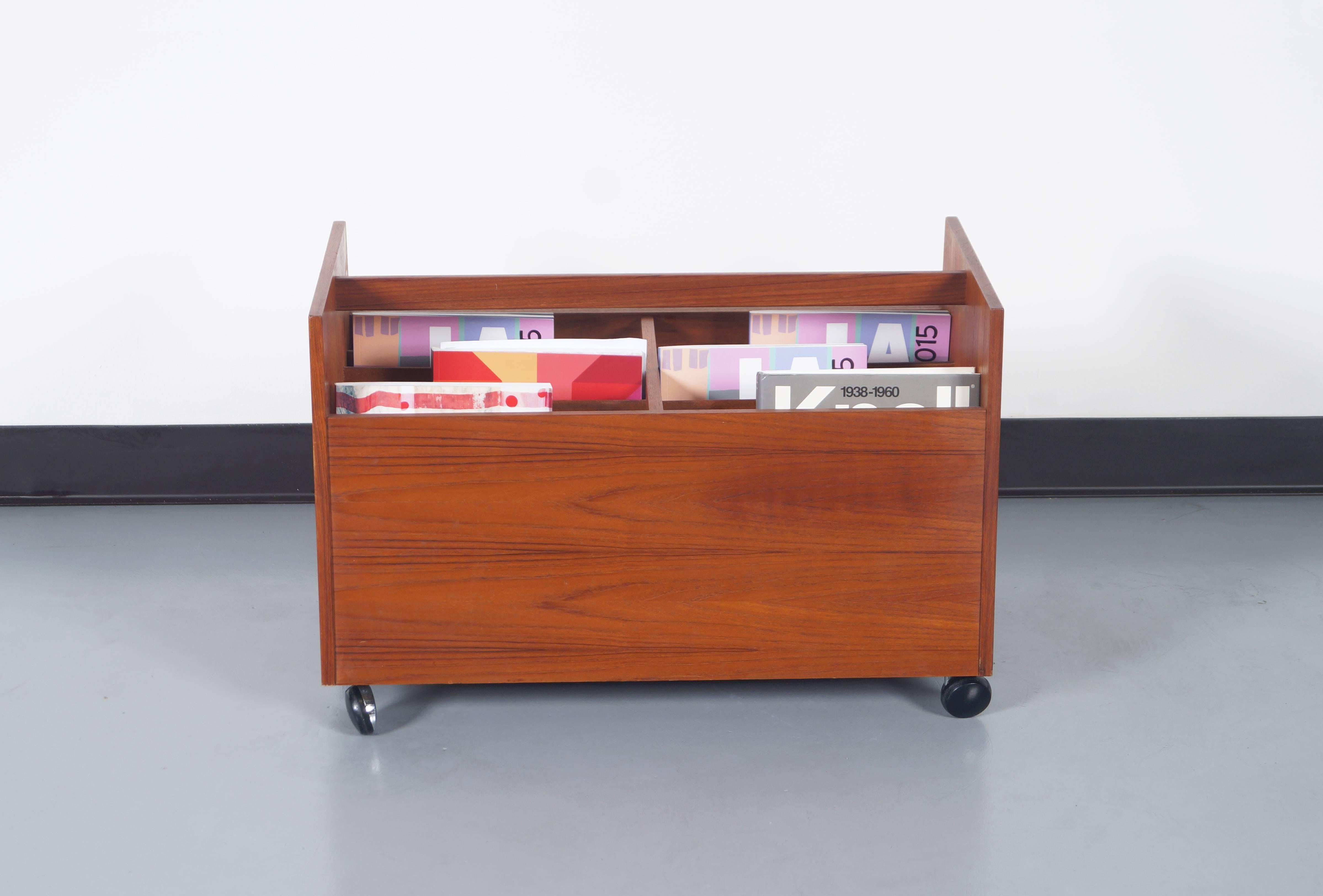 Fabulous vintage teak rolling magazine or record stand designed by Rolf Hesland for Bruskbo in Norway, circa 1960s. Features a trapezoid-shaped design in which you can appreciate the fine grains of teak throughout the entire structure of the piece.