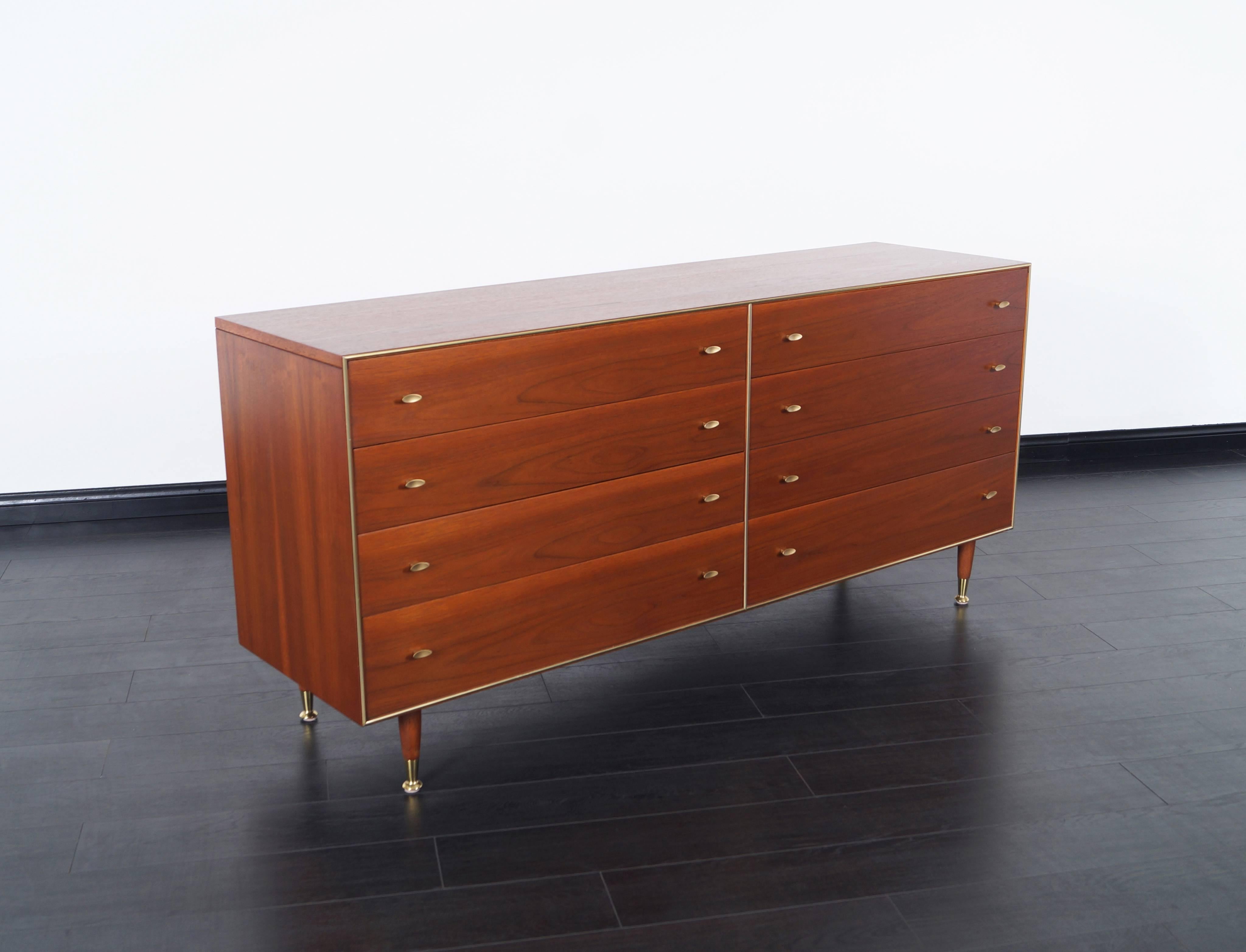 Mid-Century Modern walnut dresser by R-Way. Features seven dovetail drawers with solid brass feet. Handles are stained in a brass finish.
