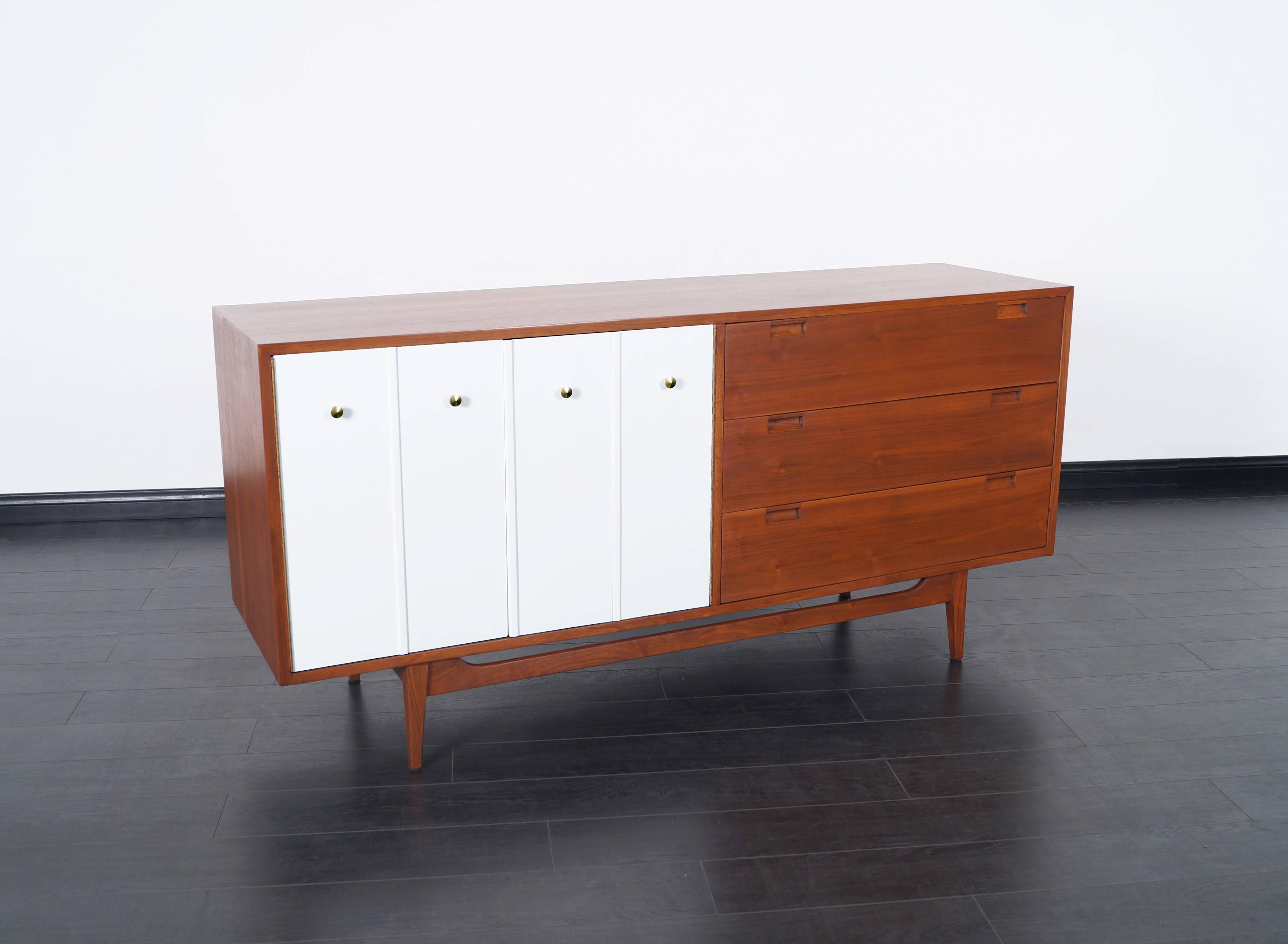 Vintage walnut credenza by American of Martinsville. Features a total of six dovetail drawers, three drawers are hidden behind white lacquer Bi-Folding doors.