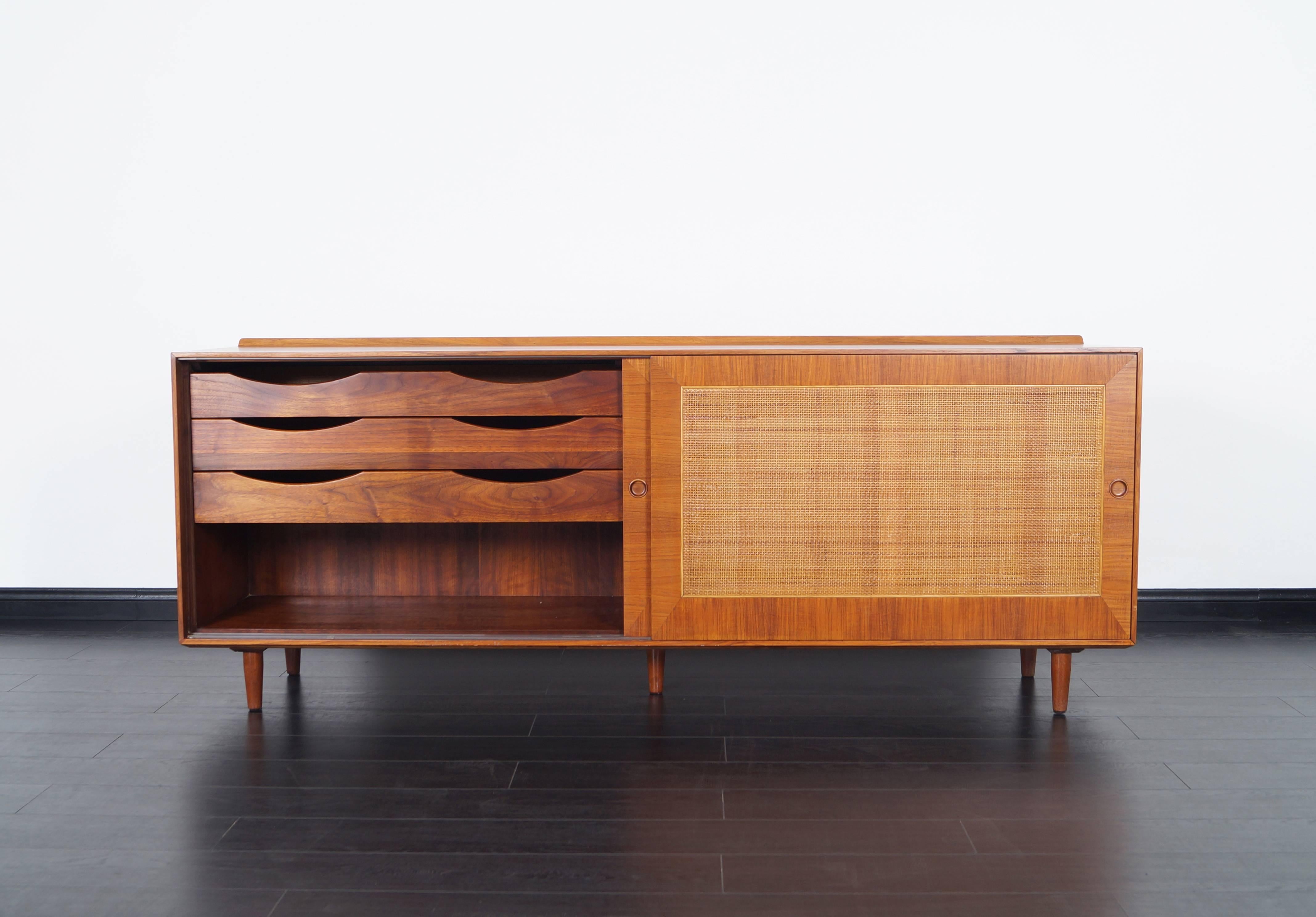 Fabulous vintage teak credenza designed part of Finn Juhl's, 1952 collection of design for Baker Furniture. Features two sliding doors which conceals an adjustable shelf and three pull-out drawers.