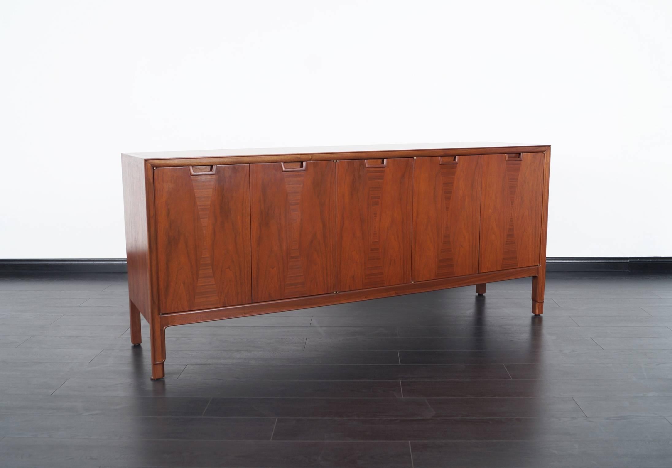 Mid-Century walnut credenza by John Stuart for Janus Collection. Contains three dovetail drawers to the left and one shelf on the right side.