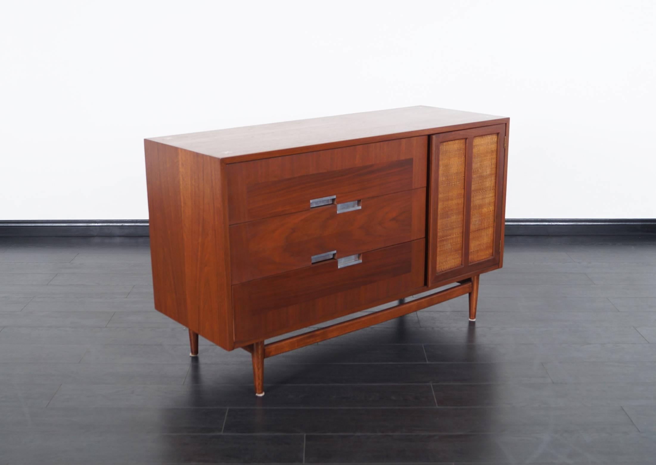 Vintage walnut credenza by American of Martinsville. Features three dovetail drawers, with one shelf behind cane door.
