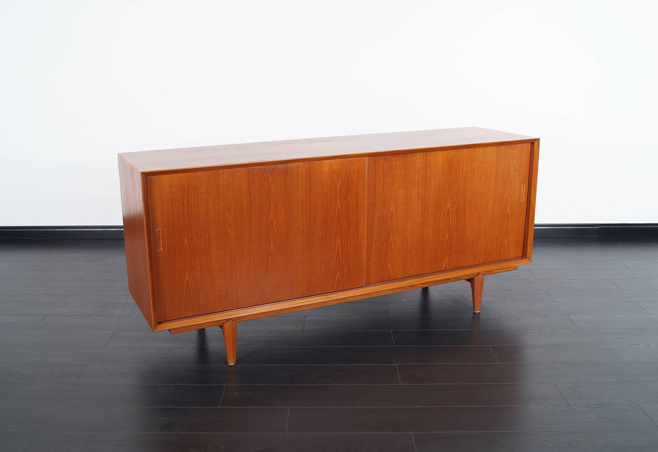 Danish modern teak sideboard features five pull-out drawers with an adjustable shelf on the left side, and one adjustable shelf to the right.