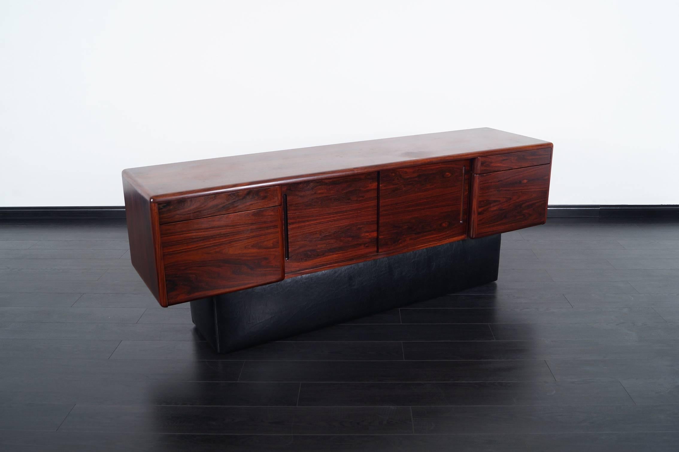 Danish modern Brazilian rosewood credenza. Features four drawers, two sliding doors, and leatherette base.