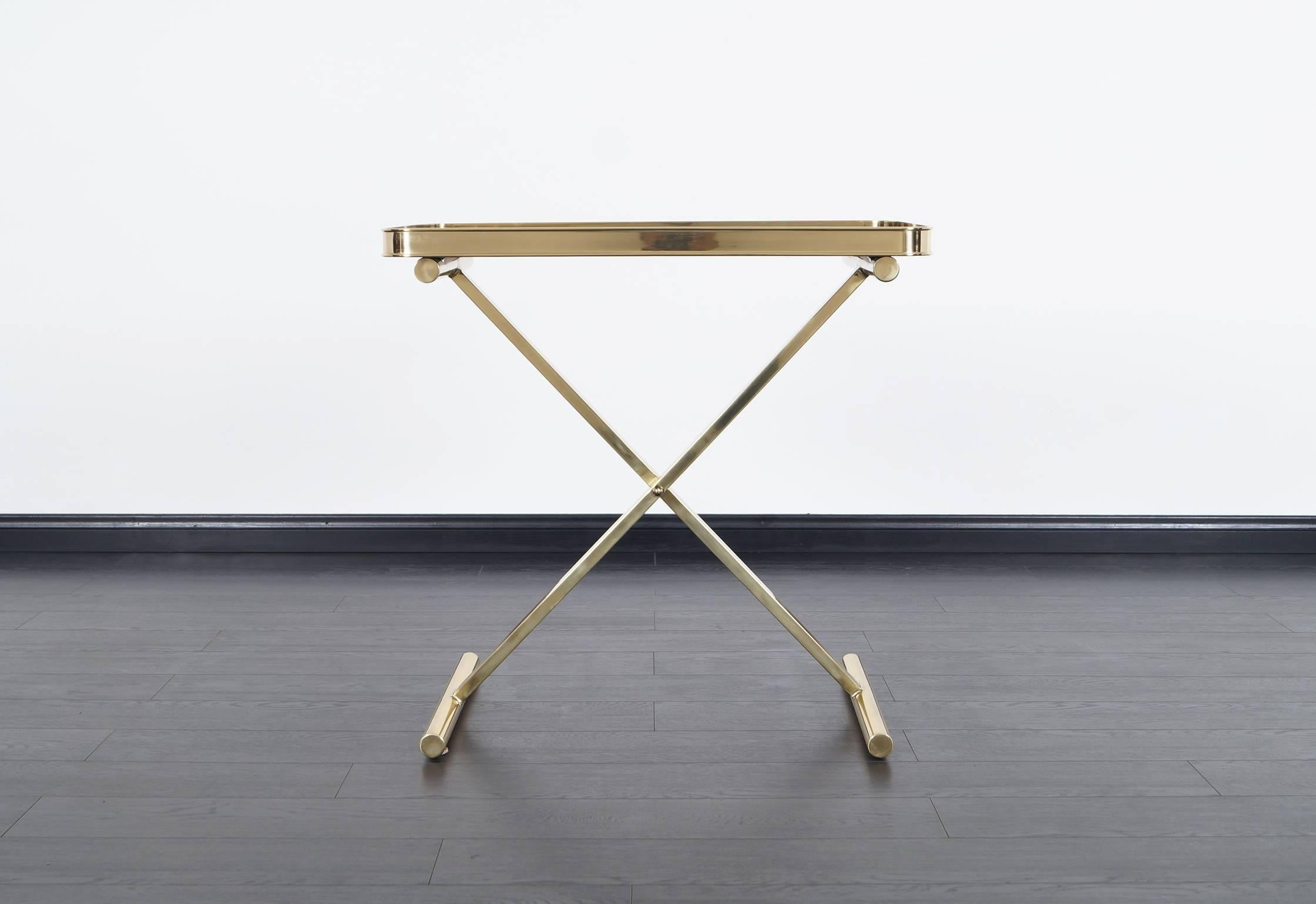 Beautiful Italian brass table tray. Features a brass X-shaped base with smoke glass top.