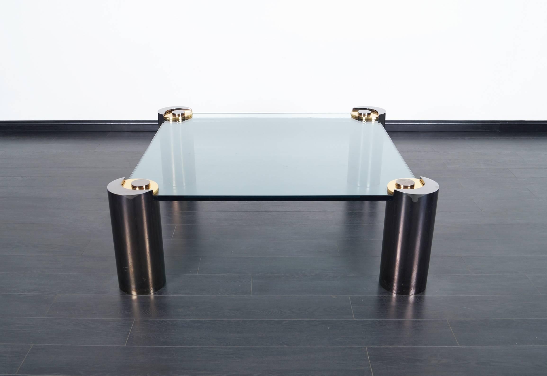 This stunning rare glass & gunmetal coffee table was designed by Karl Springer. Features four sculptural gunmetal legs with thick cantilevered glass top. One of the table base is signed Karl Springer.