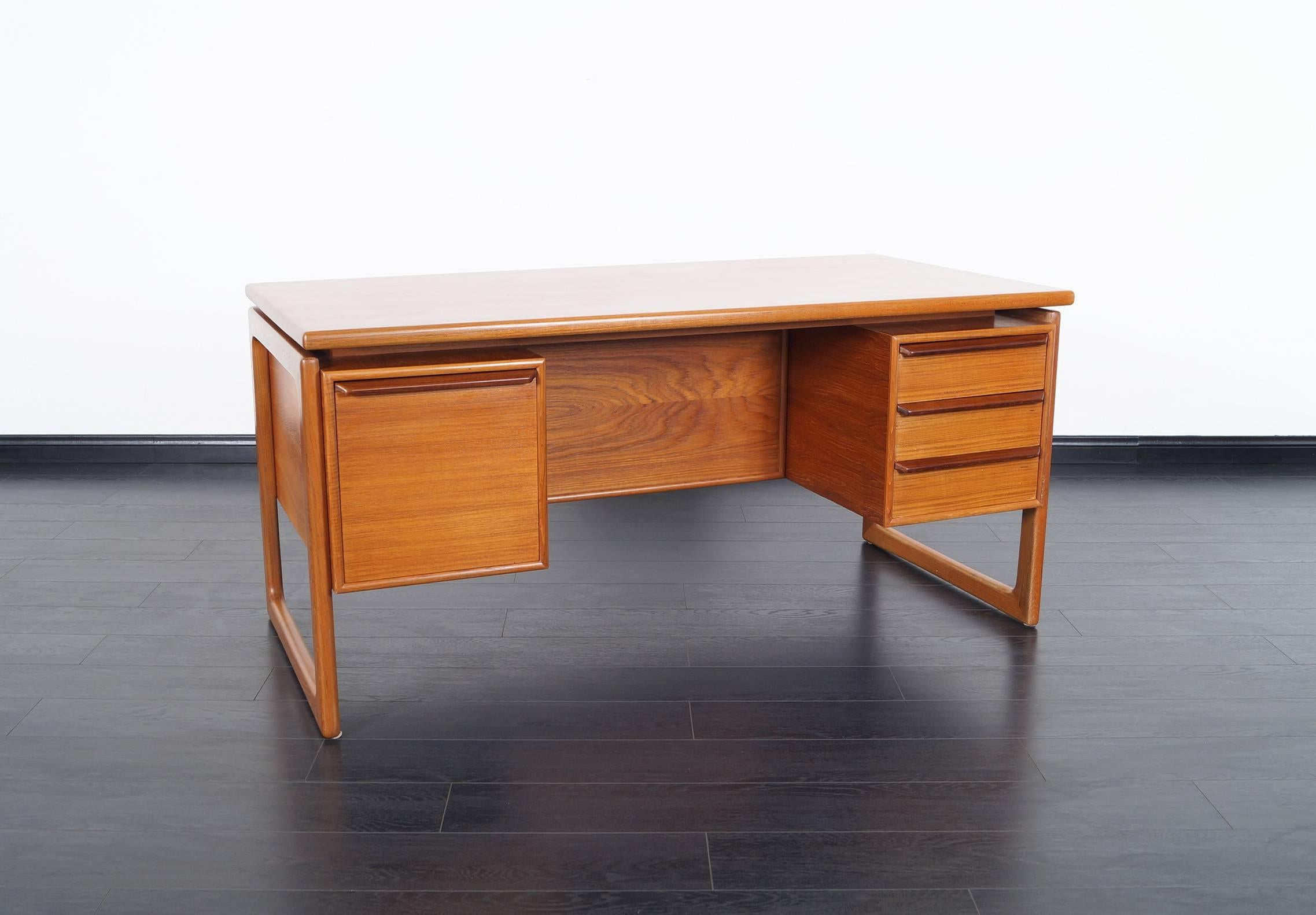 Danish modern teak desk, features three drawers on the right side and one file cabinet on the left side. A rear storage space for display.