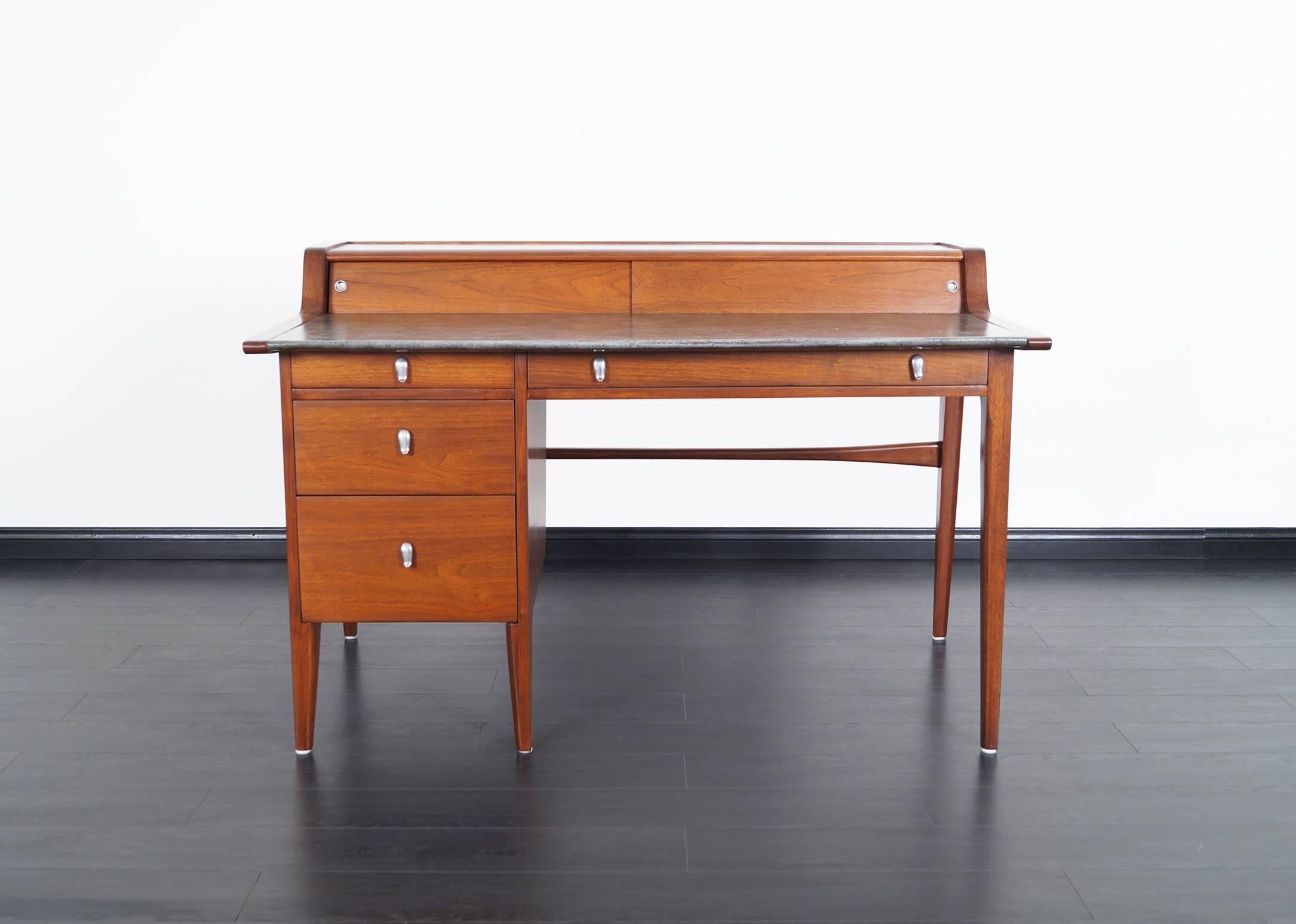This modernist desk derives it's beauty from it's line and incredible craftsmanship. It was designed by John Van Koert for the Drexel Profile series. The back is amazing as the front, so it can be displayed in the middle of a room. Desk features a
