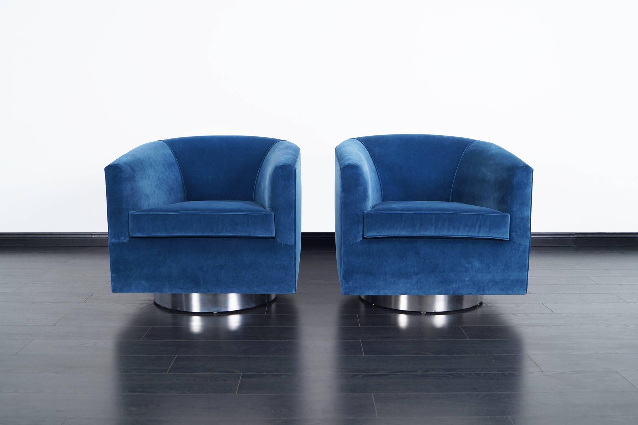 A stunning pair pf swivel lounge chairs designed by Milo Baughman. Each chair has a circular chrome base that swivel with ease. They are extremely comfortable. The chair are newly upholstered in a beautiful blue velvet.