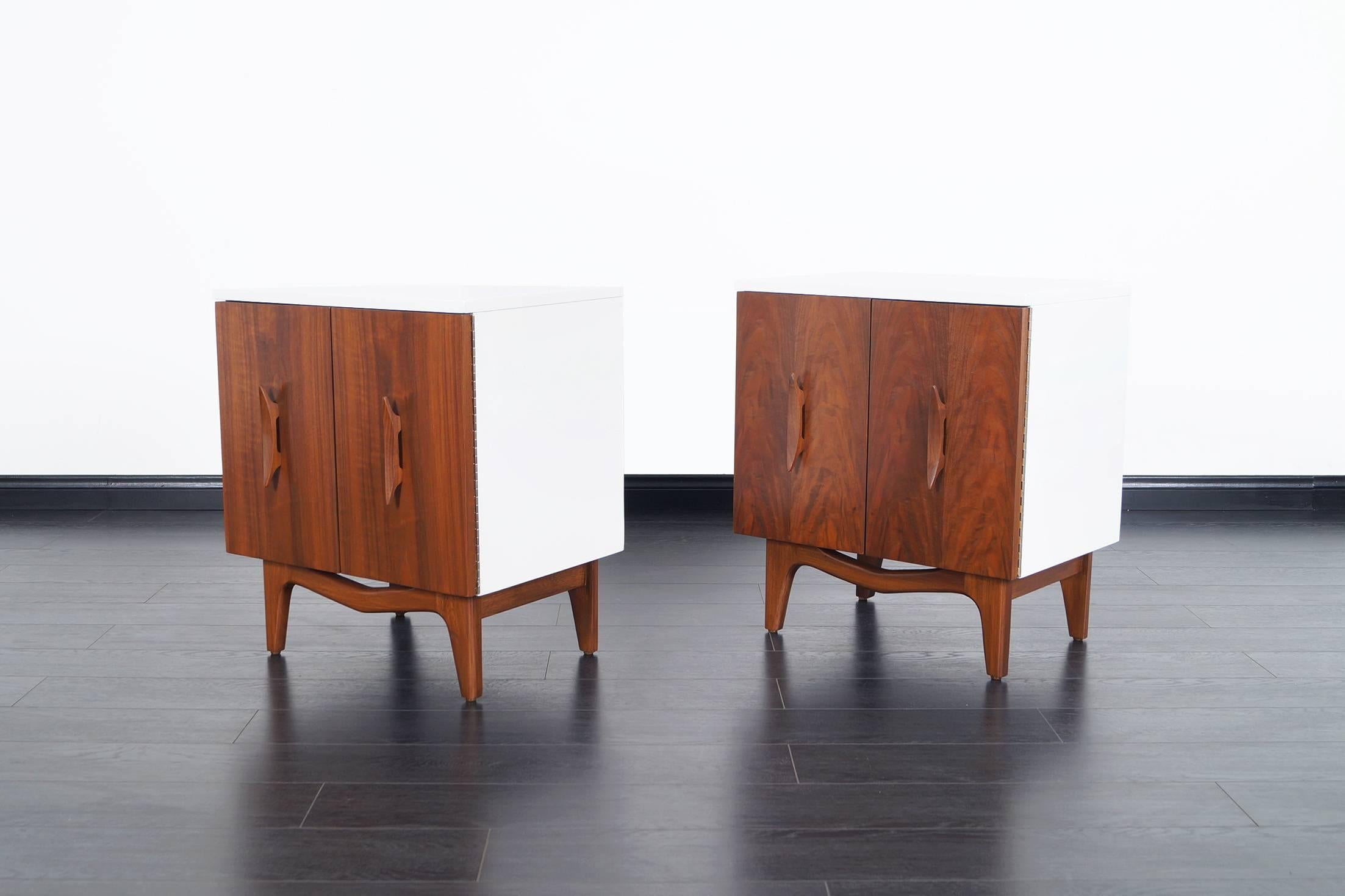 Pair of beautiful Mid-Century walnut and lacquered nightstands. Features sculptural handles and legs.