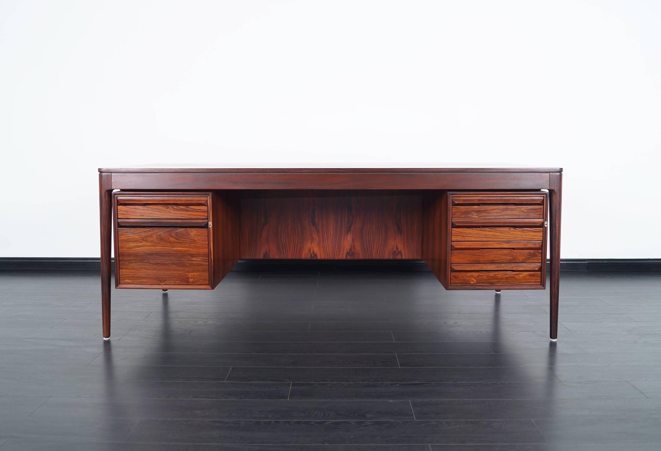 Monumental rosewood desk designed by Torbjørn Afdal for Bruksbo. Features four drawers on the right side and one drawer with a large file cabinet on the left side.