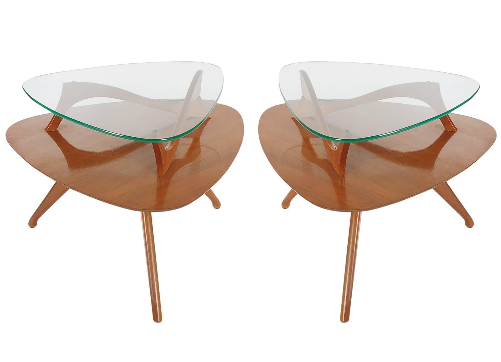 An unusual matching pair of two-tier end tables from the 1960's. They feature walnut construction with floating glass tops. 

In the style of: Adrian Pearsall, Gio Ponti