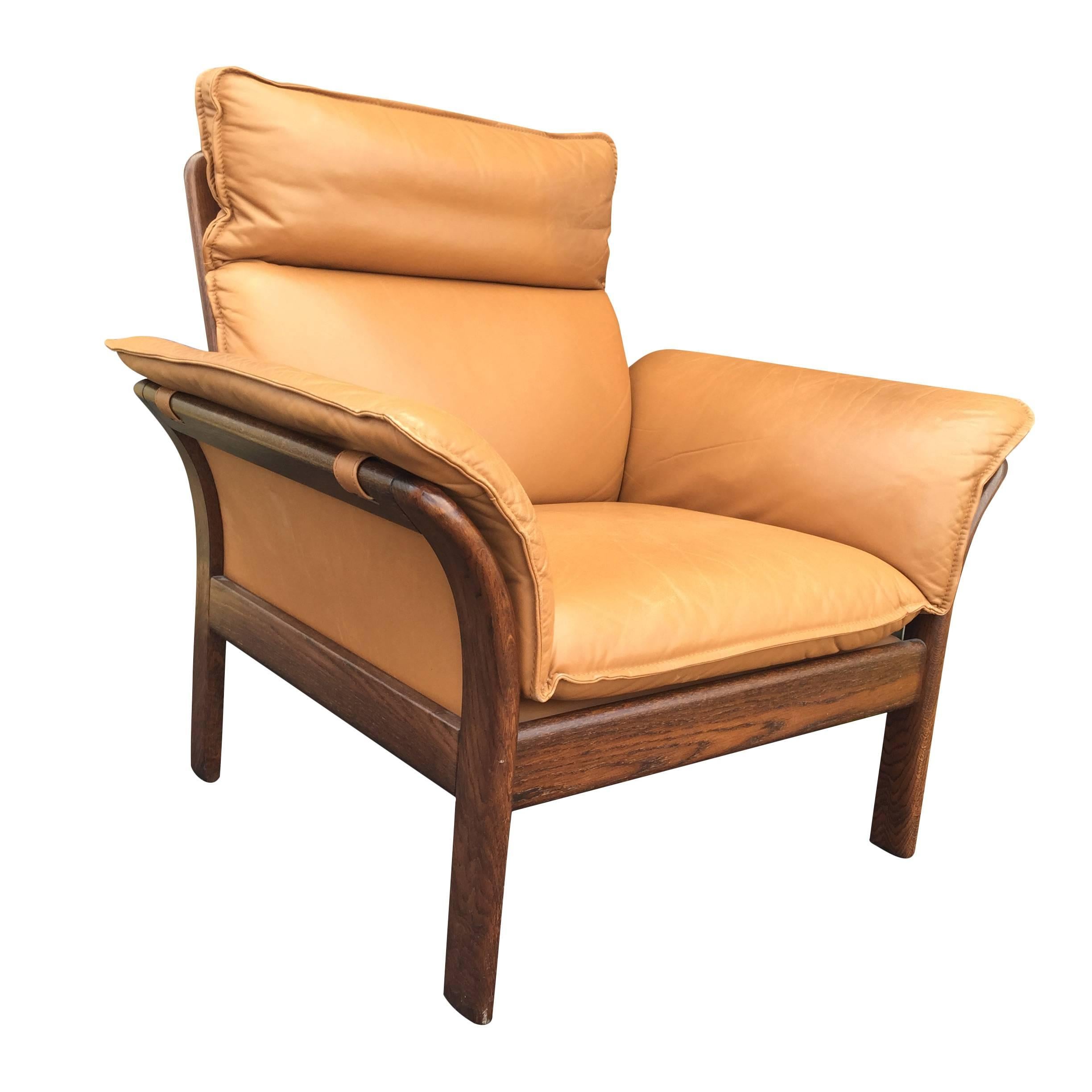 This chair has great lines and is comfortable! A sleek rosewood frame supports overstuffed camel colored leather cushions. Frame is is sturdy with some fading, leather shows minimal wear, namely some darkening on armrests and surface scratches on