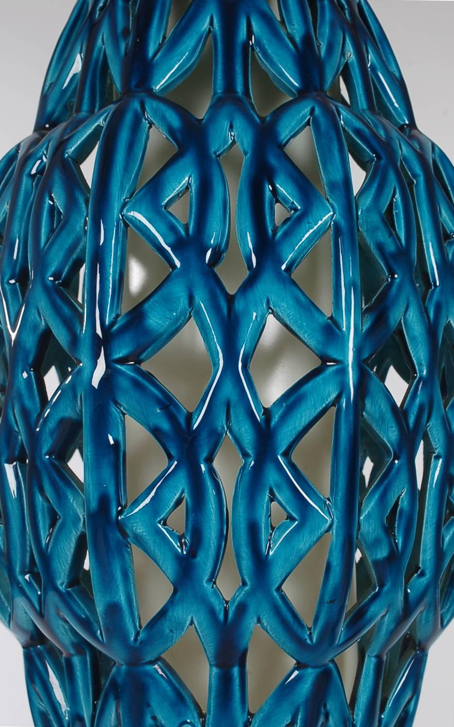 A beautifully crafted basket weave lighting fixture done in a blue glazed ceramic pottery. It has 12 feet of hanging chain and can be plugged into standard outlet or hardwired if desired.

In the style of: Bitossi, Bagni, Gambone.