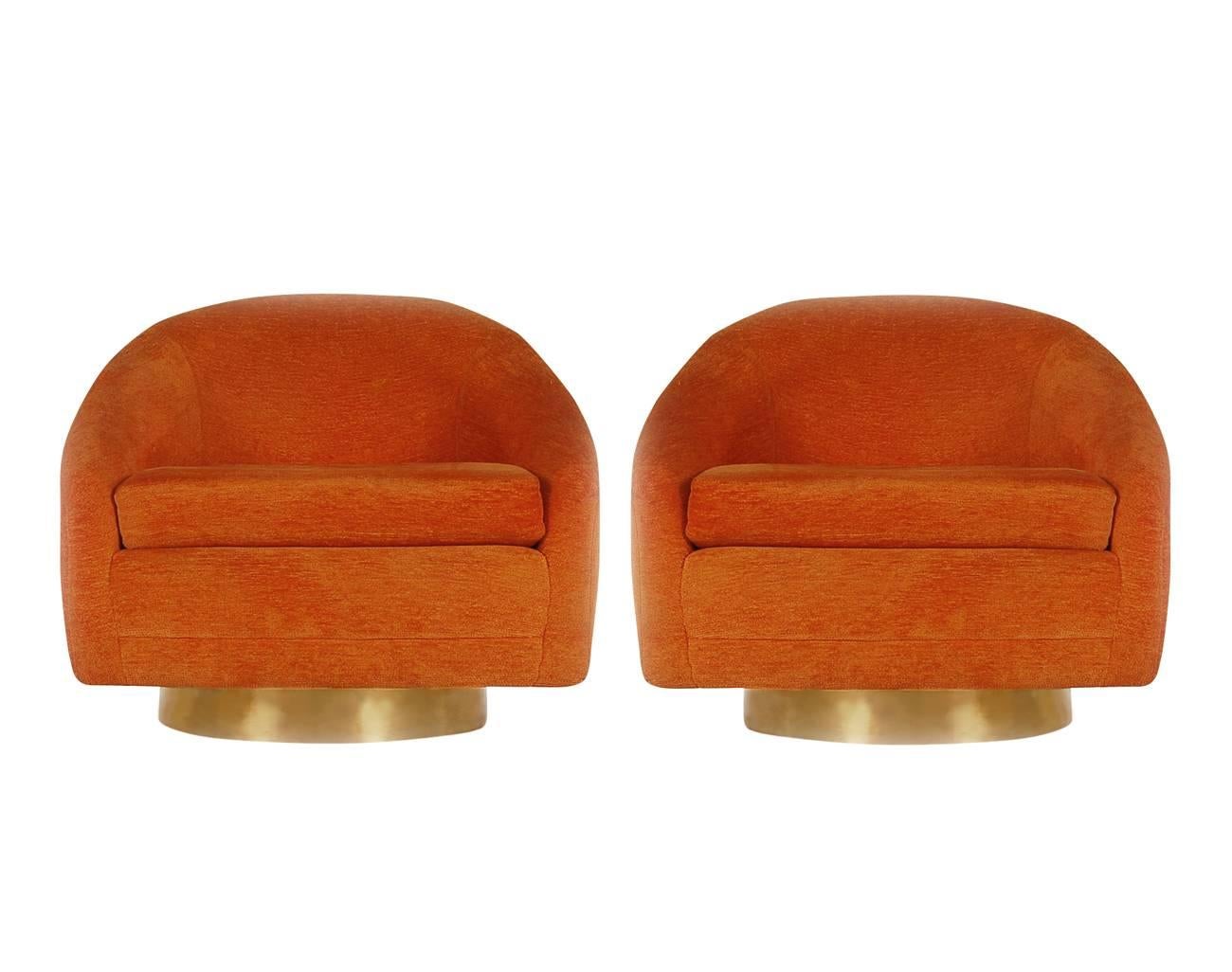 A handsome matching pair of swiveling and reclining club chairs after Milo Baughman for Thayer Coggin. They feature brass circular bases with the original orange upholstery.

In the style of: Harvey Probber, Ward Bennet.