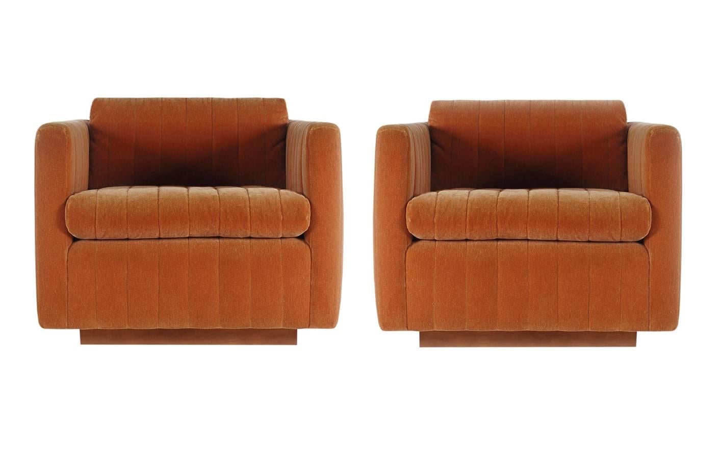 A lovely matching pair of club chairs designed by Milo Baughman for James. These chairs feature Art Deco style ribbed upholstery with walnut plinth bases.