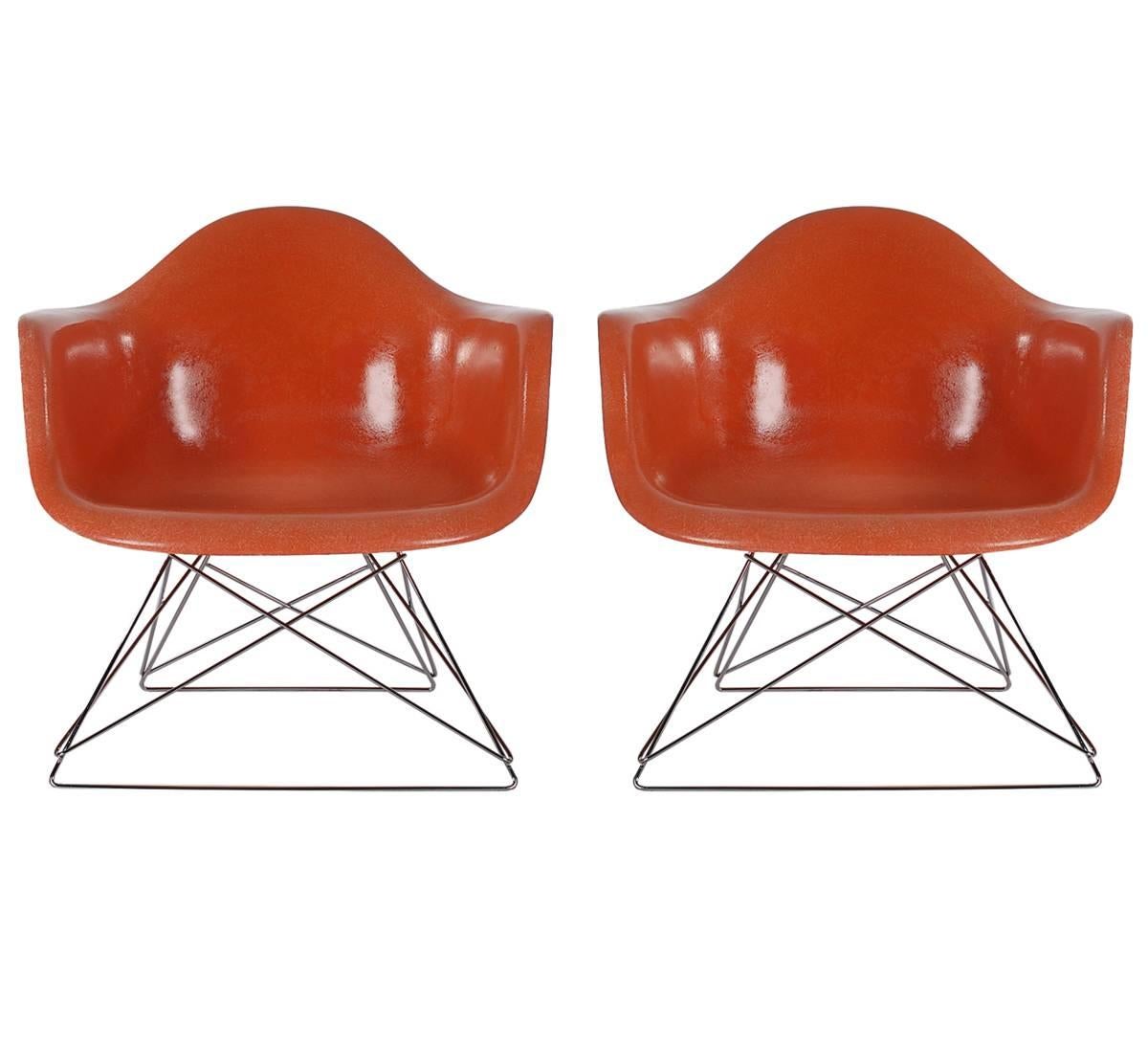 Here we have an iconic design classic from the Mid-Century Modern period. This vintage fiberglass shell chair was designed by Charles Eames and produced by Herman Miller, circa 1972. In a vibrant retro orange color. The chair seats are vintage, and