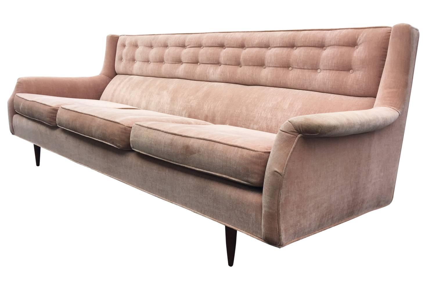 This sofa has lovely lines, walnut legs and a tufted headrest. The padded lumbar cushion makes it surprisingly comfortable. Velvet does show age and wear in the form of light fading, some staining on the underside of the seat cushions and one dime