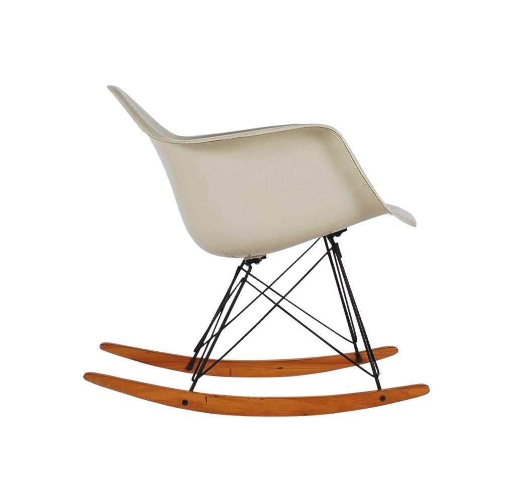 100% all original Charles Eames designed rocking chair stamped 1959 and produced by Herman Miller. It features a parchment colored fiberglass shell with original rocking base with warm honey colored maple runners. Nice warm patina.