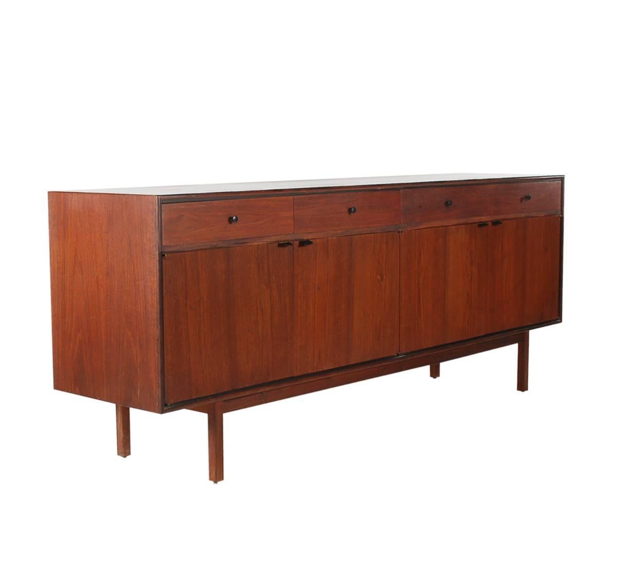 A beautiful and early cabinet attributed to Florence Knoll for Knoll, circa 1950. It features walnut construction, leather door pulls, and a super clean interior space.