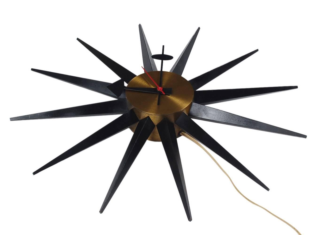 Early original starburst clock design by George Nelson and manufactured by Howard Miller Clock Company. It features brass inner body with black wooden spikes. Plugs into standard outlet, fully working and keeping accurate time.