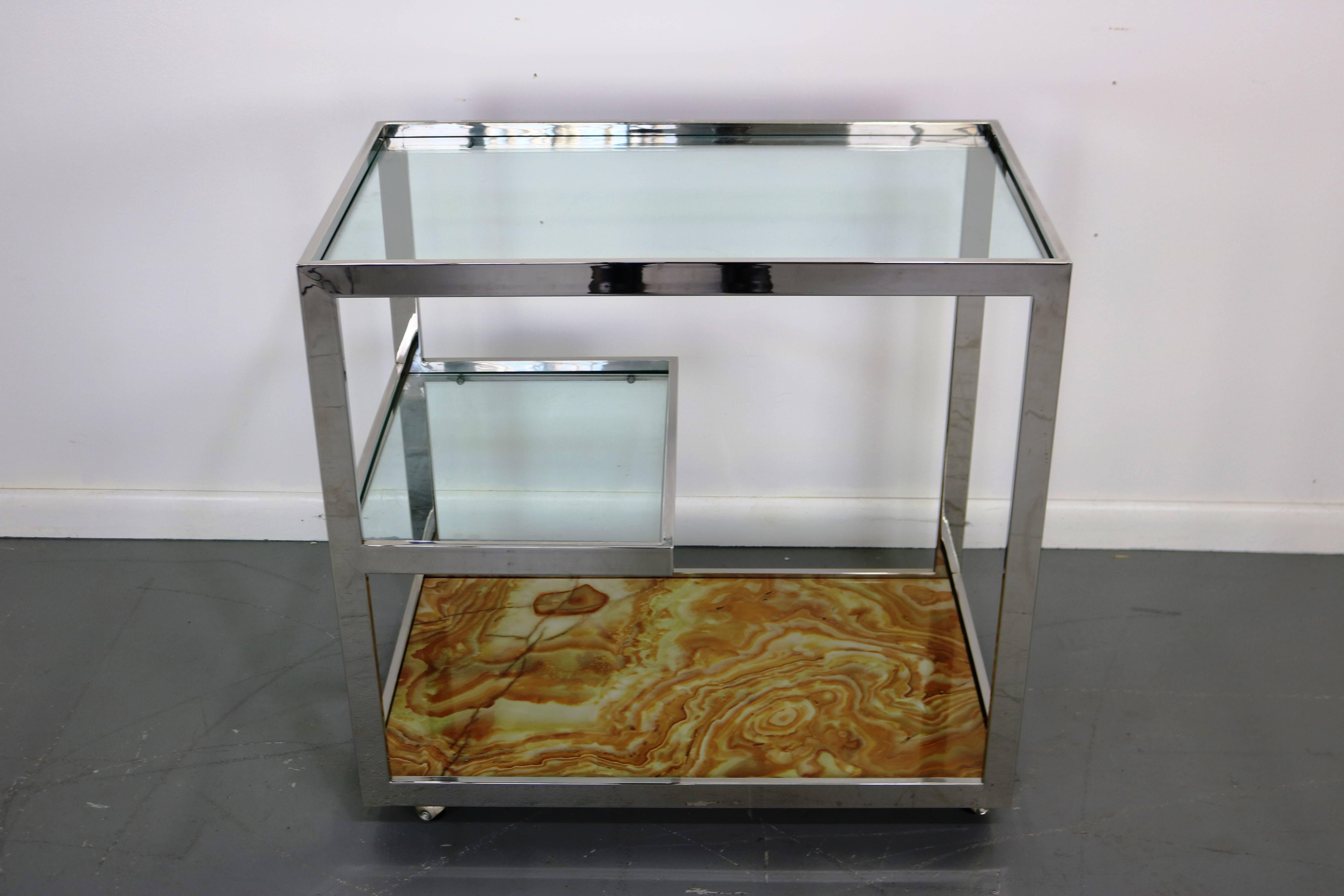 Unique and glamorous, this bar cart has a caramel onyx base, glass shelf and glass top. On casters. Fantastic condition.