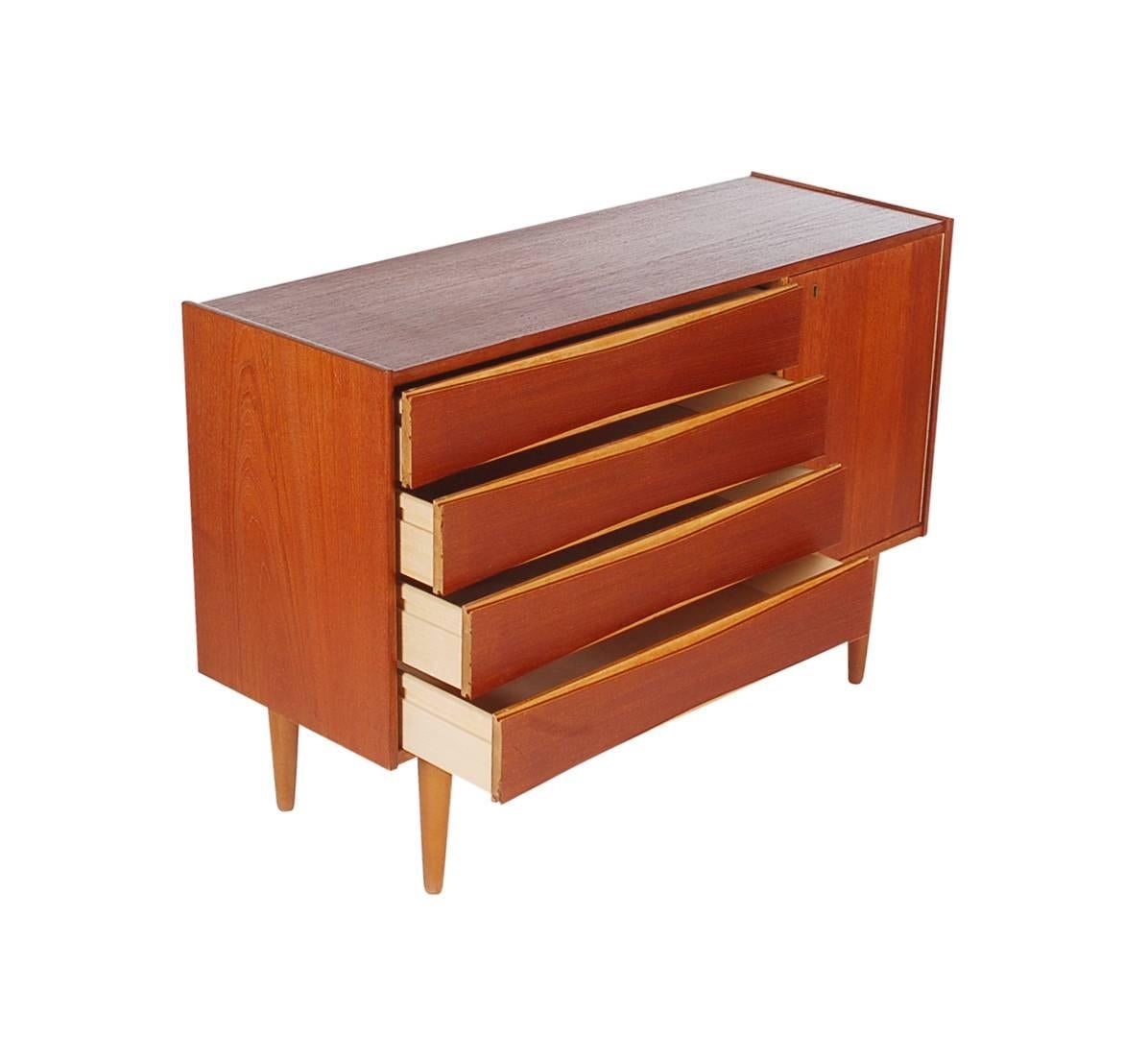 A simple and different looking designed cabinet in the manner of Arne Vodder. It features teak construction with four drawers and a storage area with shelf.