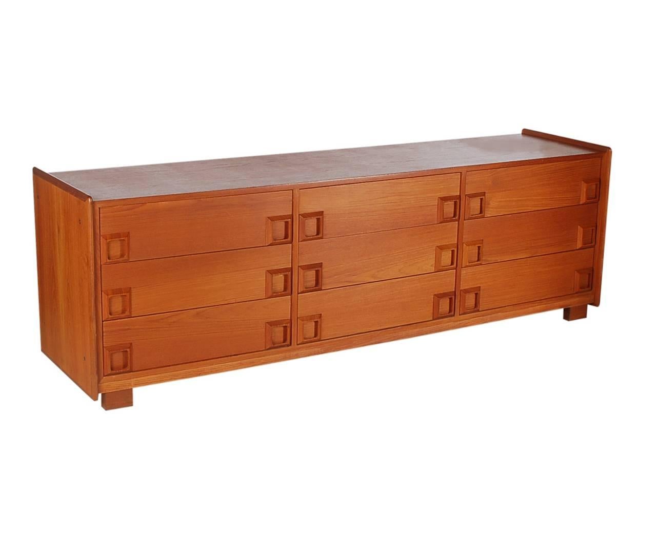 A sleek low profile nine-drawer teak dresser in the manner of John Stuart. It features teak construction and square recessed pulls.