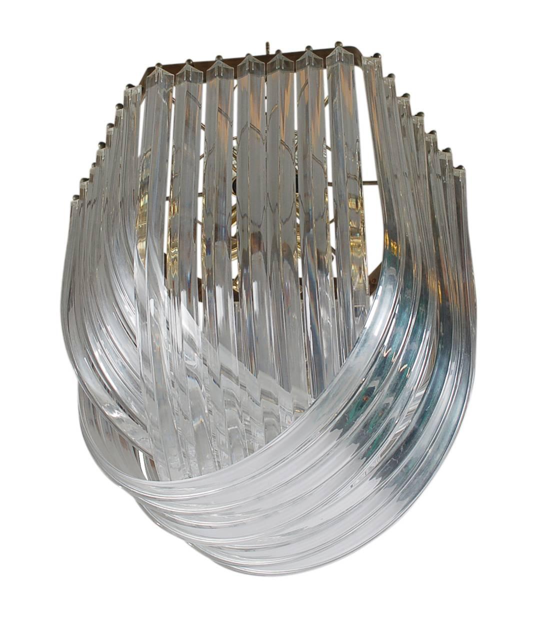 A strikingly beautiful Hollywood Glam chandelier. It features brass framing with several curved Lucite strands.