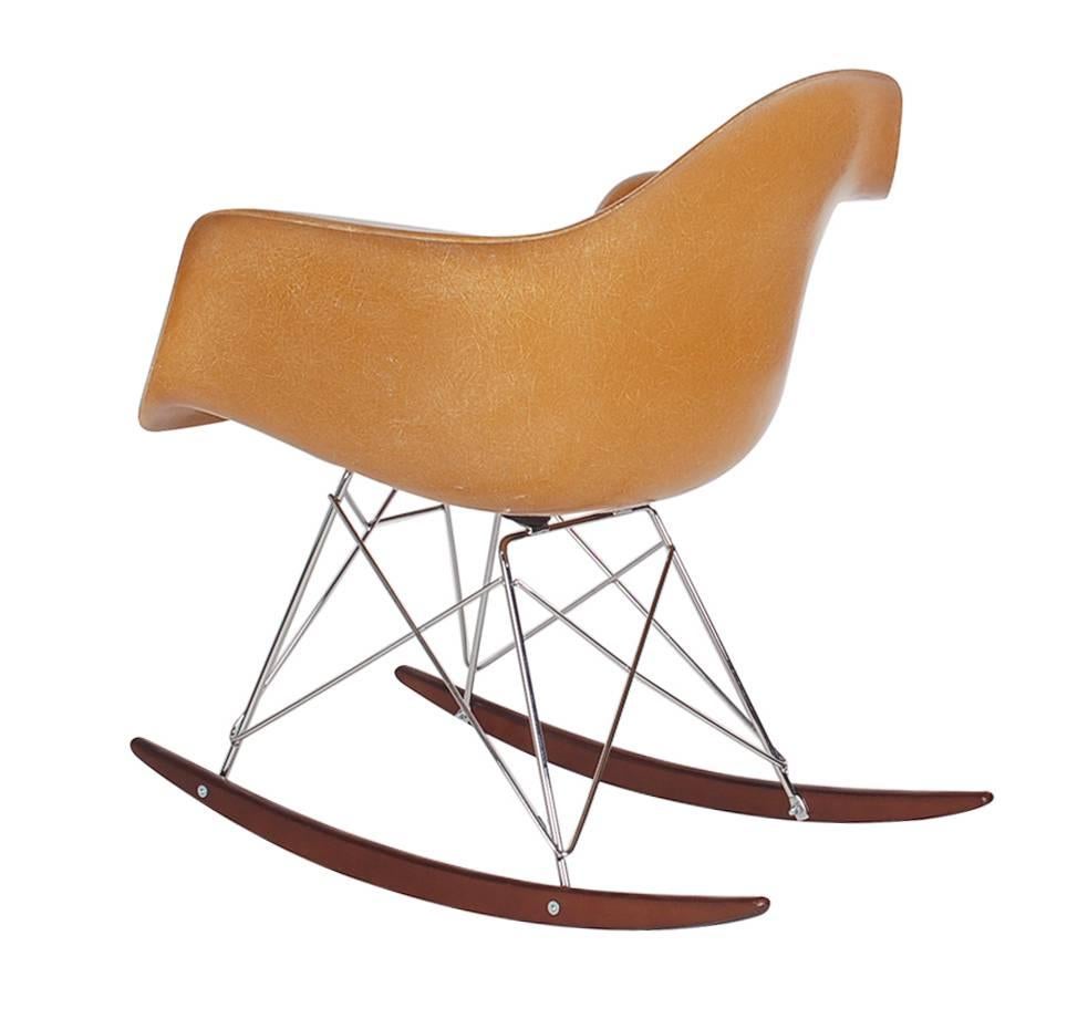 A beautiful fiberglass rocking chair designed by Charles Eames for Herman Miller. This hard to find color is "Dark Ochre". Chair is vintage, circa 1960s, base is a newer reproduction. Embossed signature.