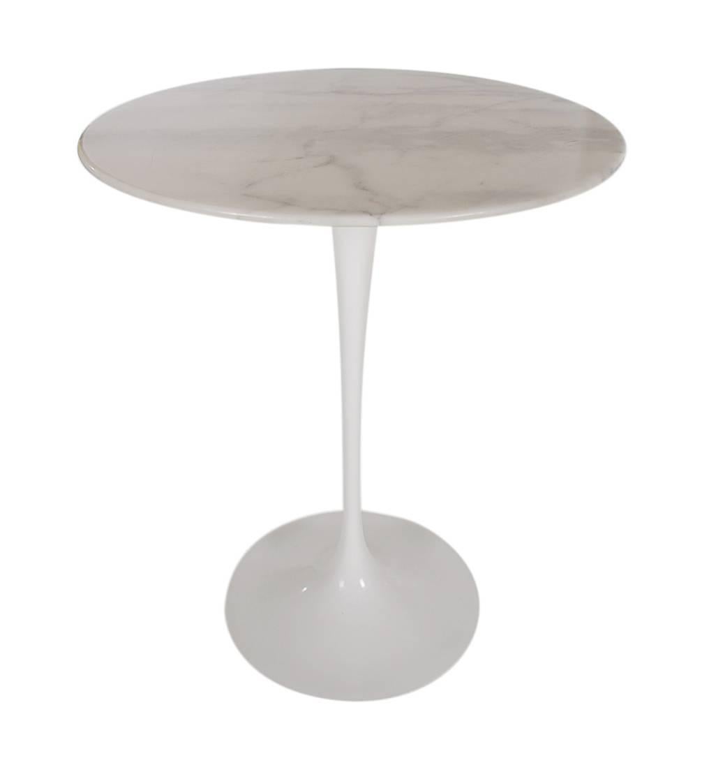 An iconic tulip table designed by architect Eero Saarinen and produced by Knoll. It features a white marble top on a white cast aluminum base. Manufacturers mark.