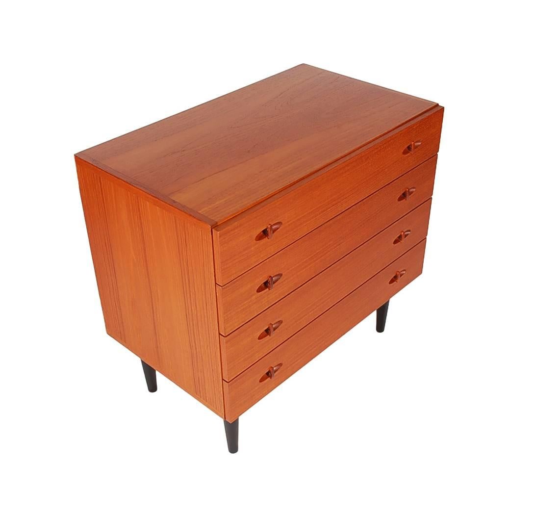A handsome Scandinavian teak chest of drawers produced in the late 1960s. It features teak wood construction, four drawers, tapered ebony legs, and beautifully designed pulls.