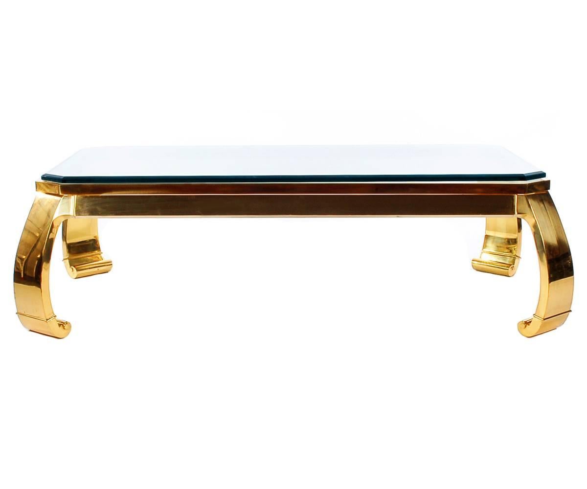 A sleek and modern brass coffee table with an Asian flair. It features a heavy solid brass frame with a thick glass top. Labelled and produced in Italy in the 1970s.
